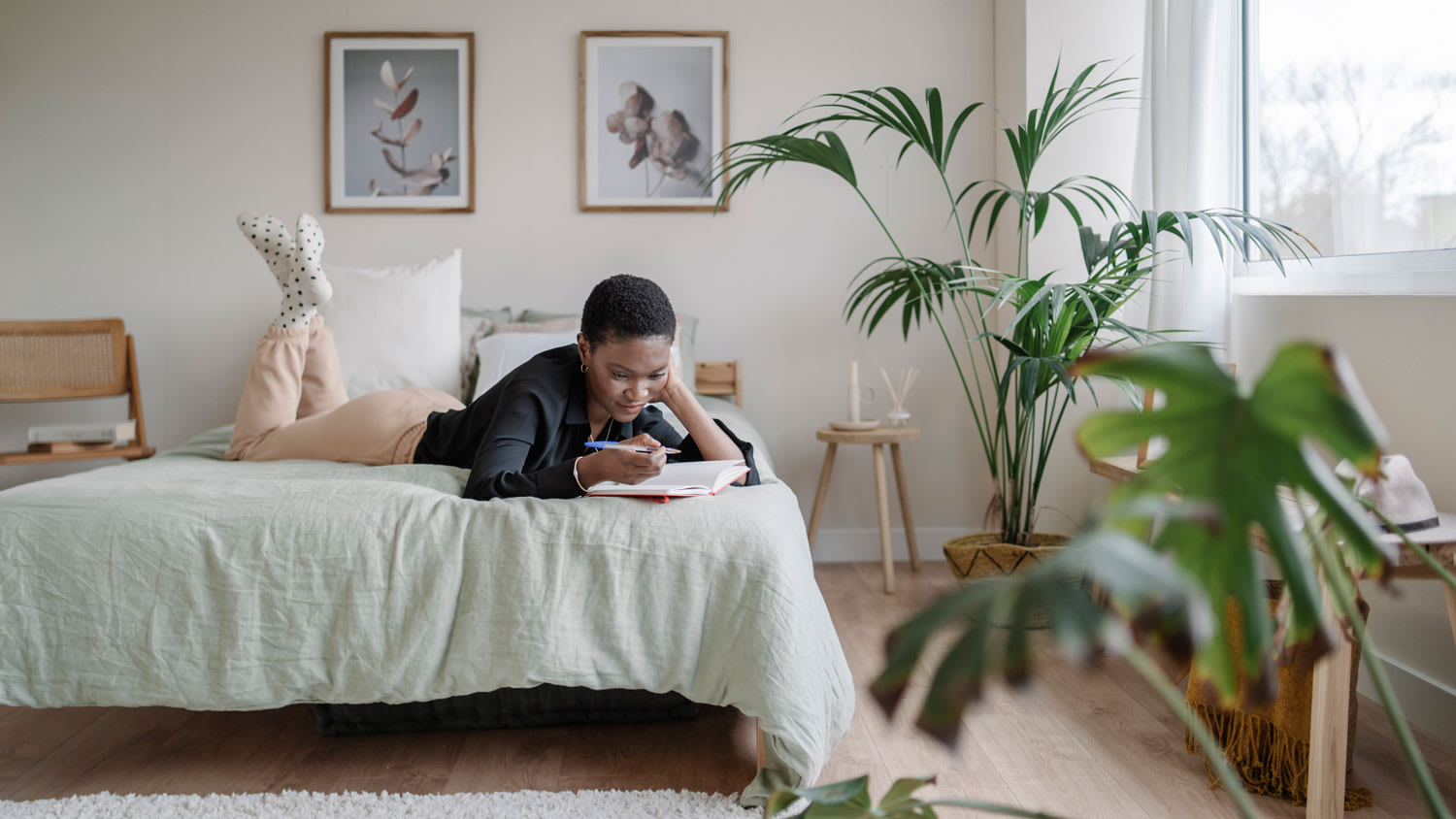 A woman writing in her notebook while laying on her comfortable bed