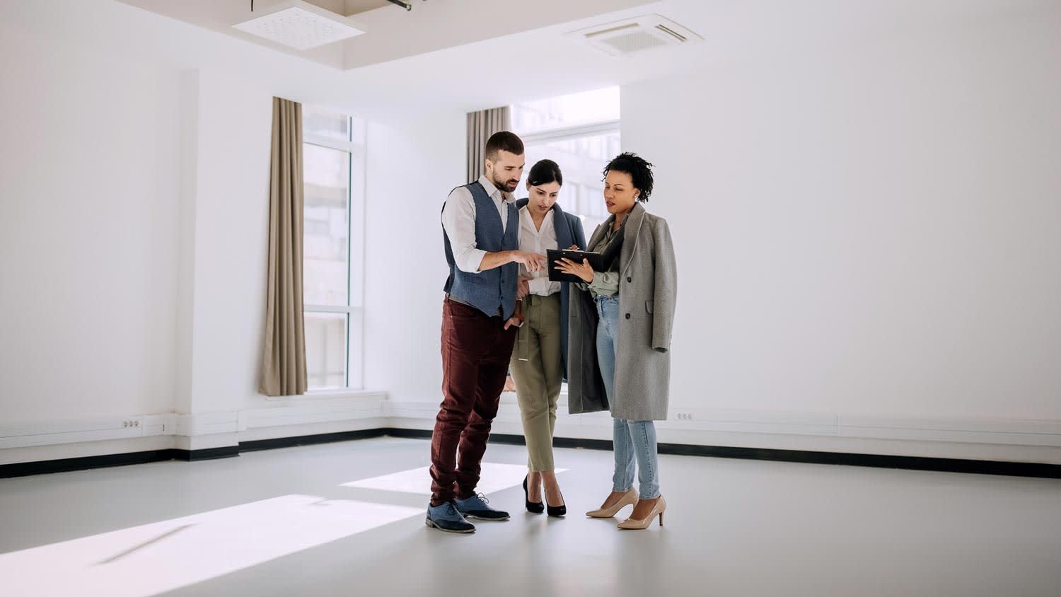 A listing agent showing a property’s plans to a couple