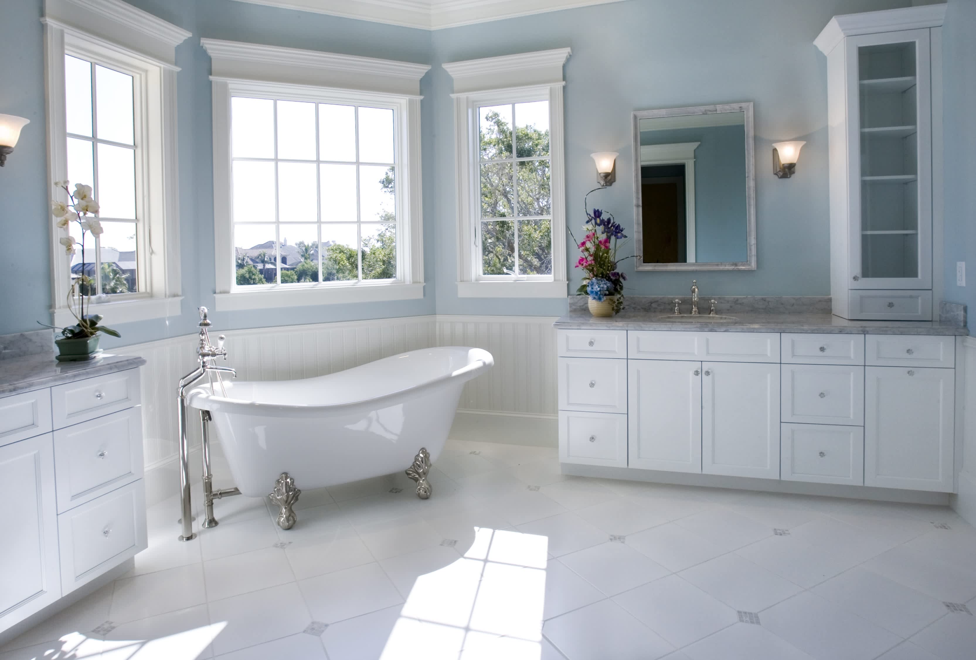A light blue bathroom with wainscoting and a white clawfoot tub