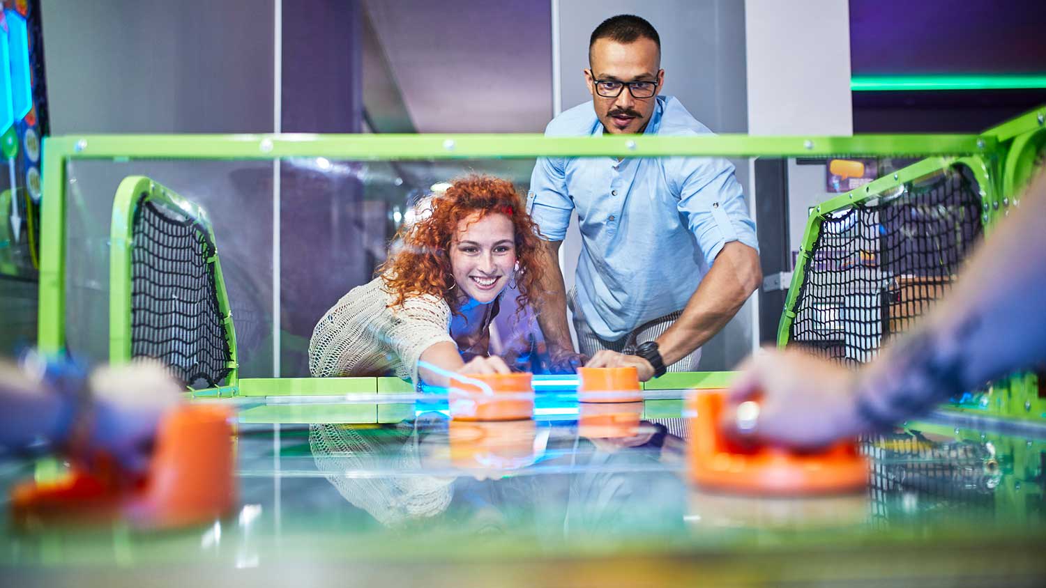 Group of friends having fun playing air hockey