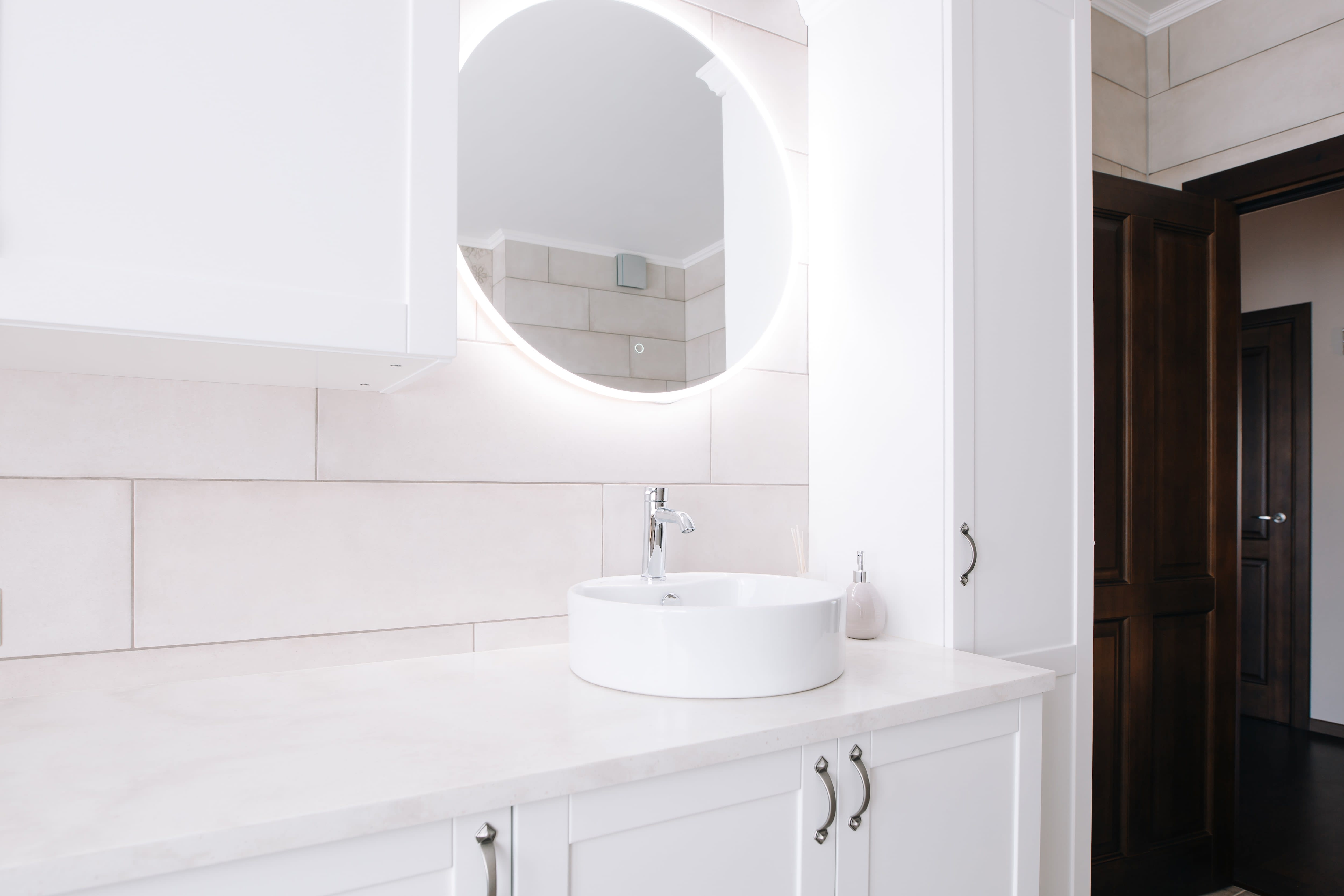 Modern bathroom white cabinets, tile walls, and a mirror with LED lighting