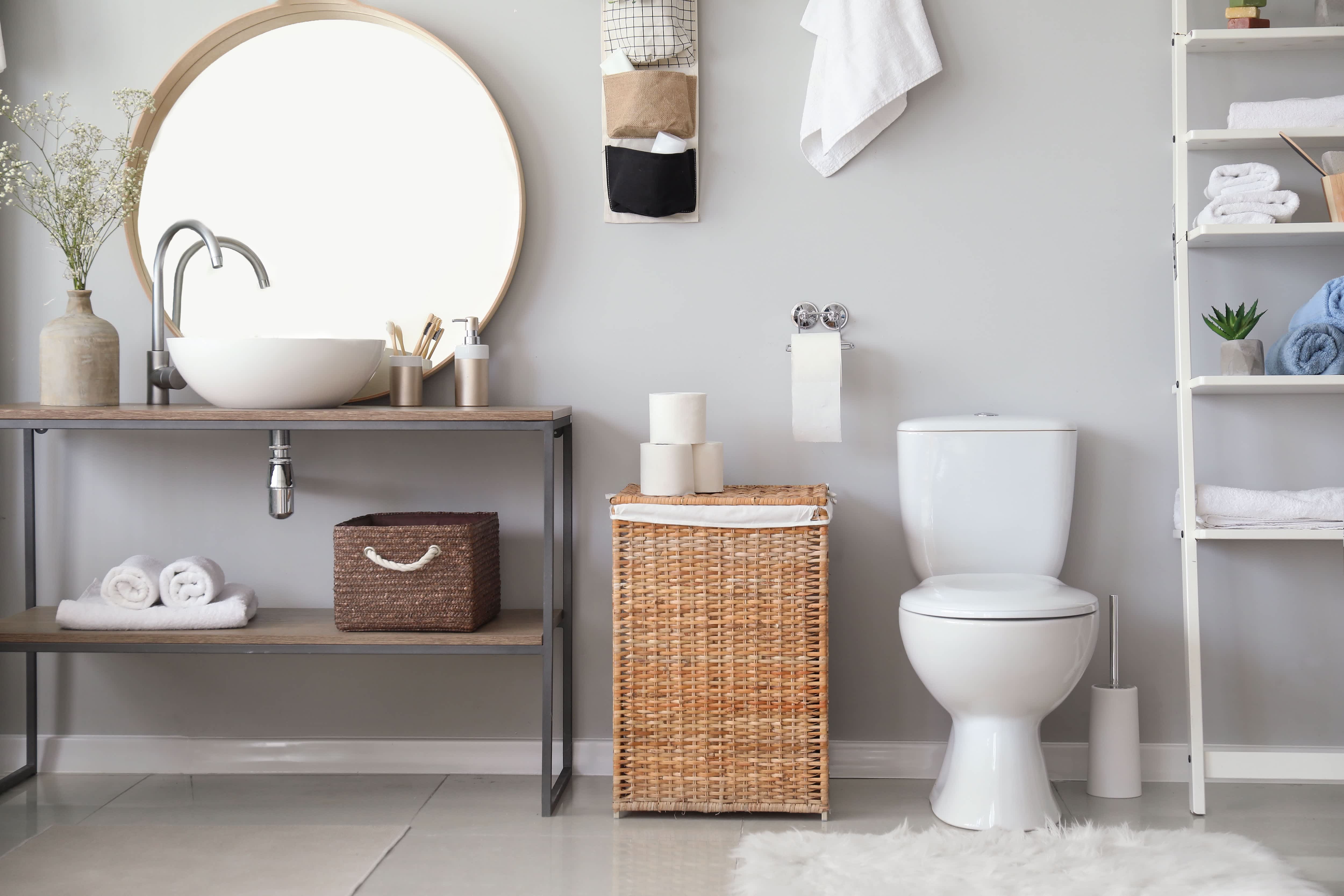 Modern bathroom with gray walls, rattan laundry basket, and exposed shelving