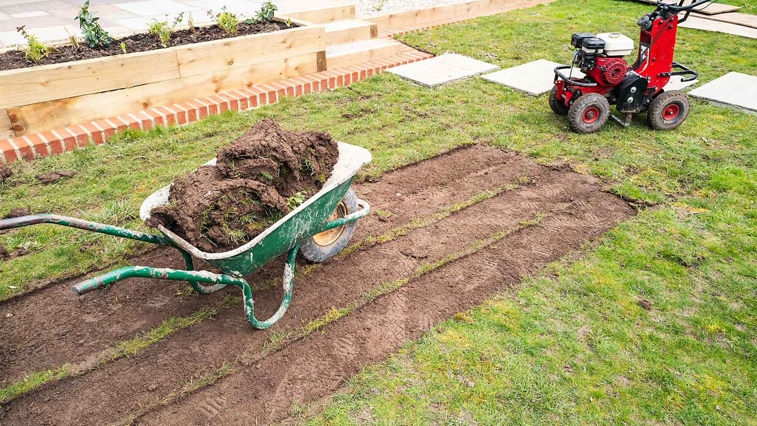 A sod cutter and wheelbarrow in a yard