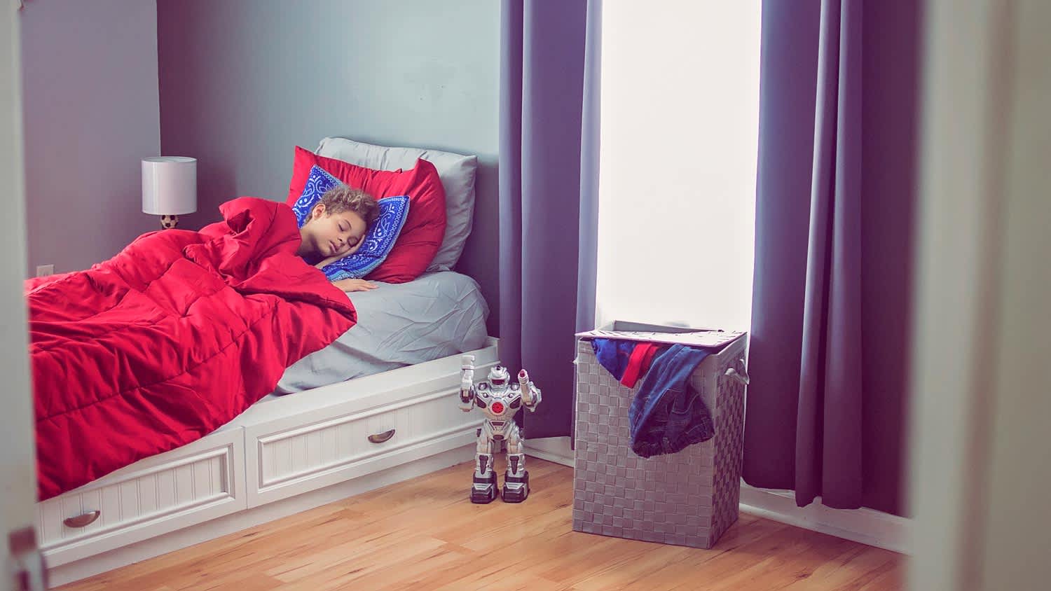 A boy sleeping in his bed next to a toy robot
