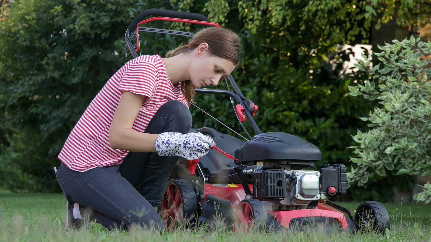 Woman checking oil level on the lawn mower