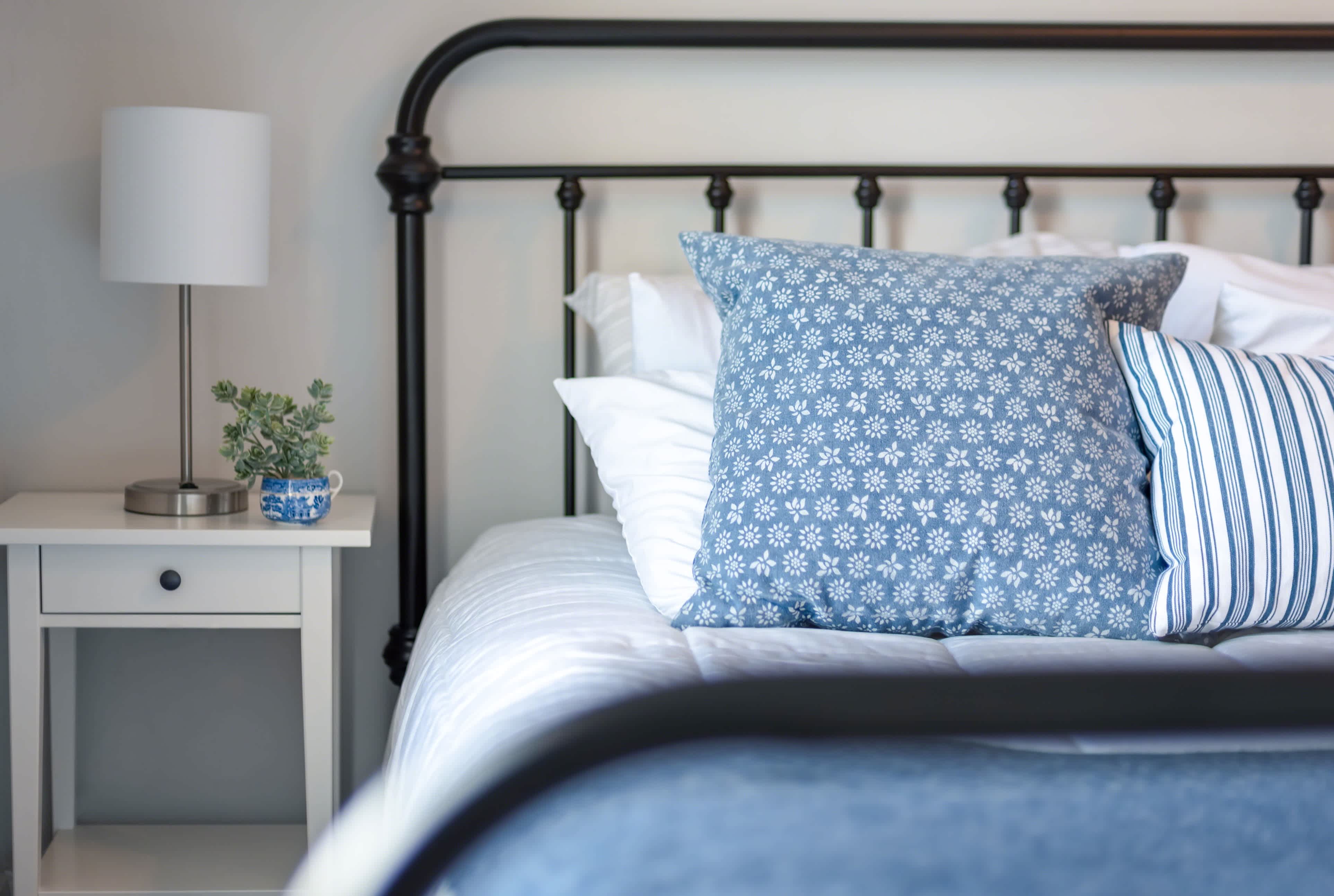 Blue and white patterned throw pillows on metal bed