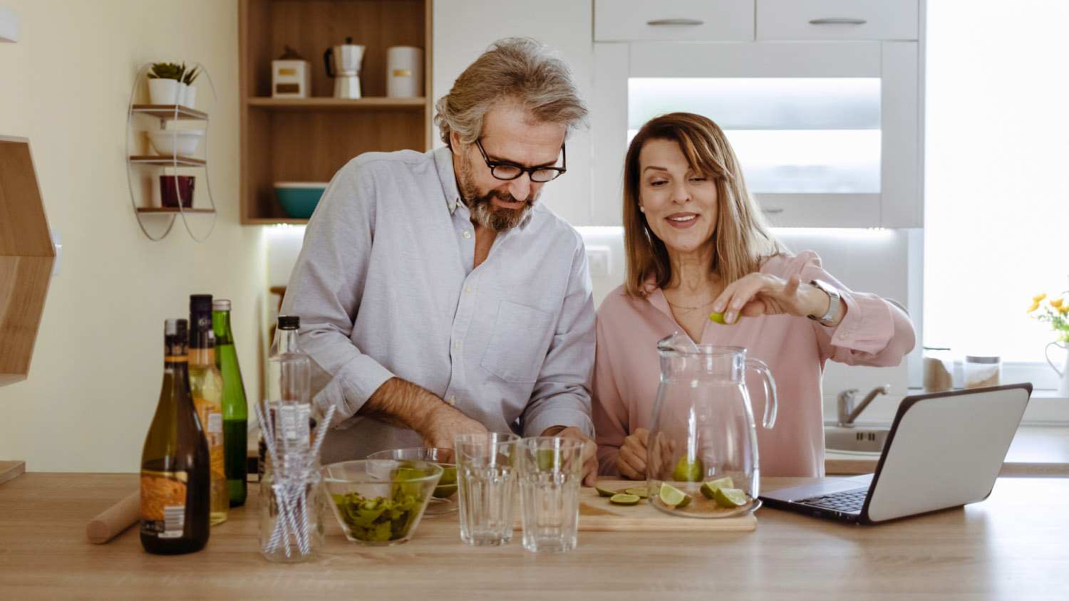 couple making cocktails in kitchen