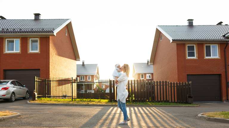 Mother kissing baby outside a row of townhomes