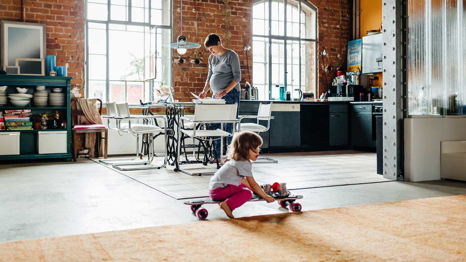 Little girl in the living room sitting on a skateboard