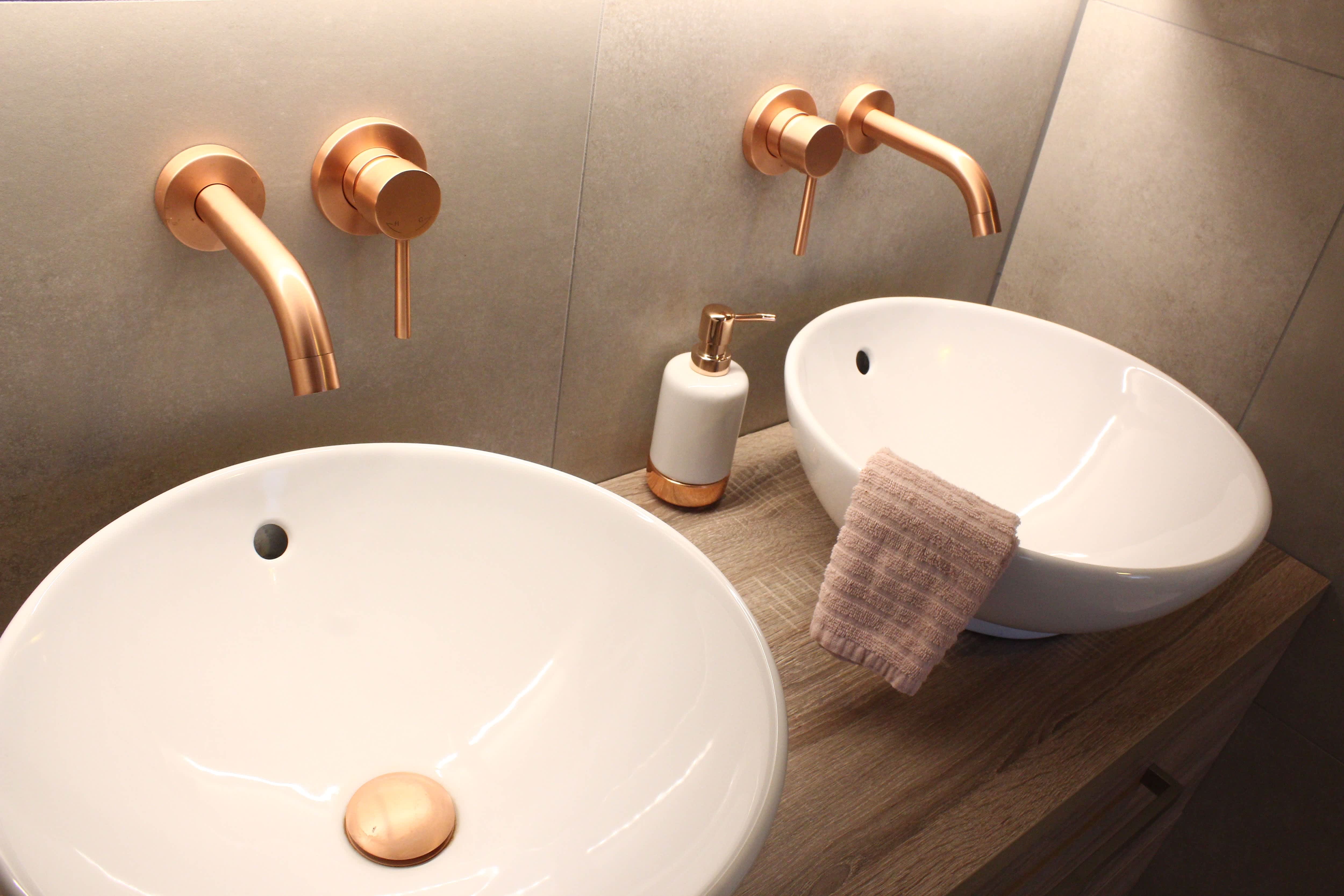 Modern bathroom with gray tile walls, wooden countertops, double sinks, and rose gold fixtures