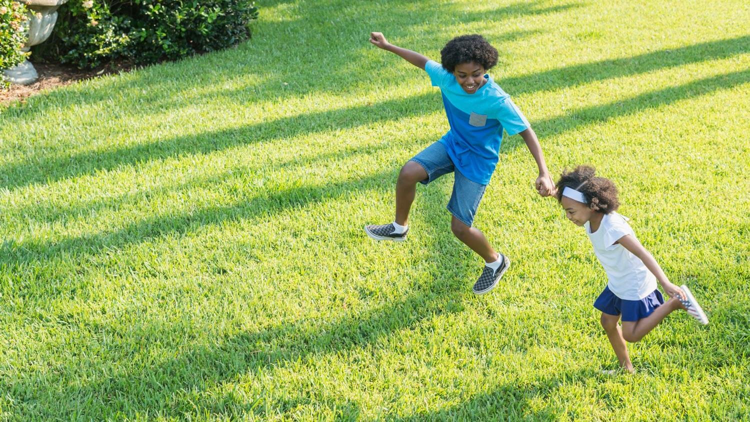 A sister and brother playing together on the lawn of their garden