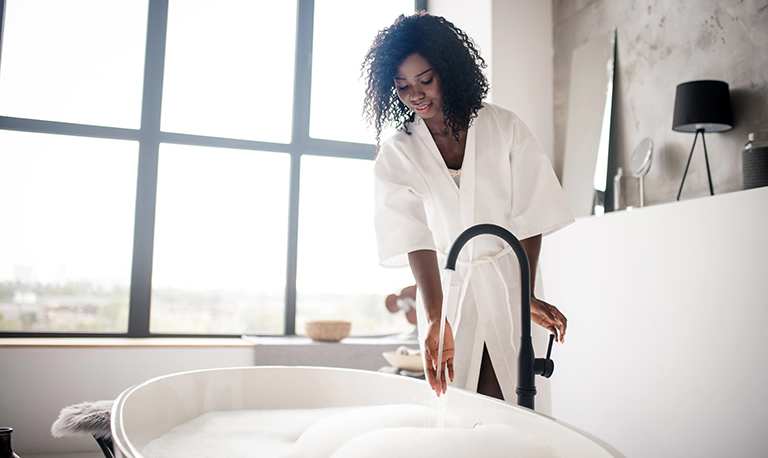 A woman runs bathwater in her tub