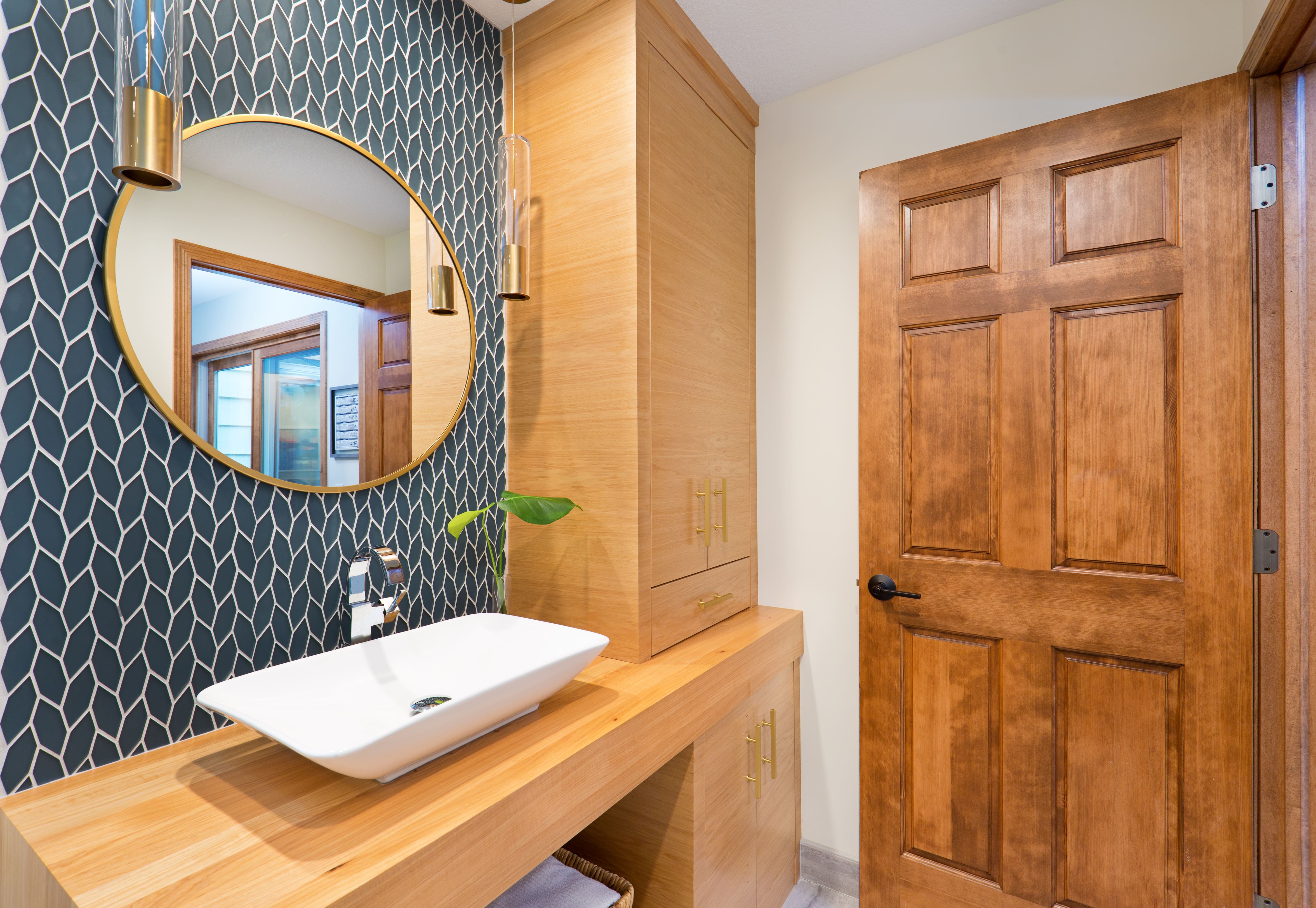Guest bathroom with built-in cabinets, white sink, and blue backsplash.