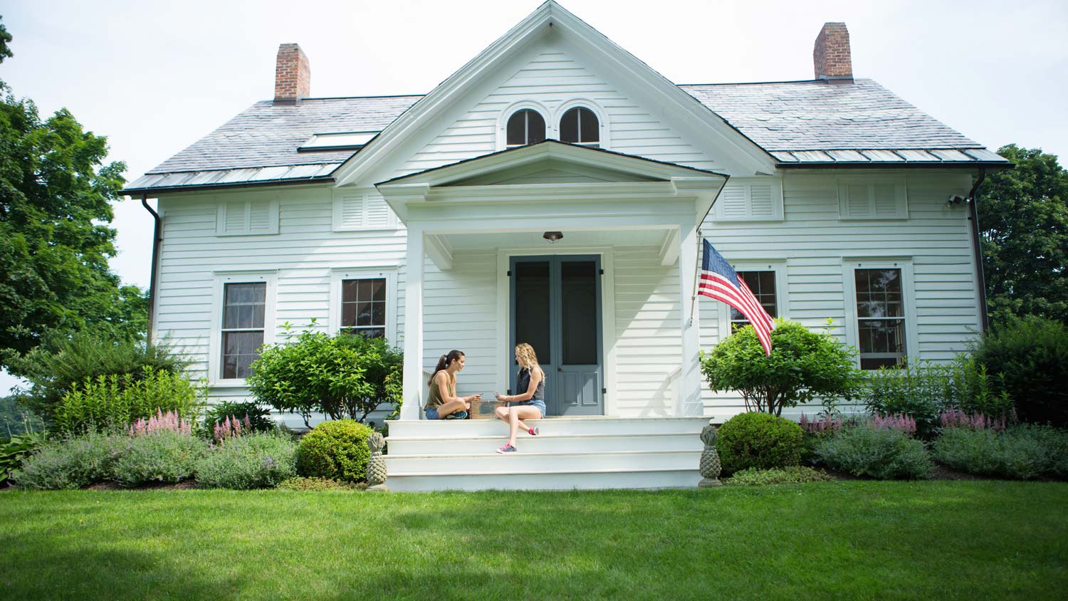 Two young women sitting at the front porch of a house