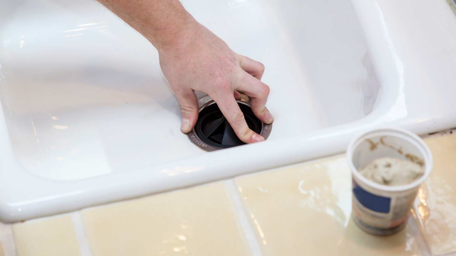Close-up of a man installing a garbage disposal in a house sink