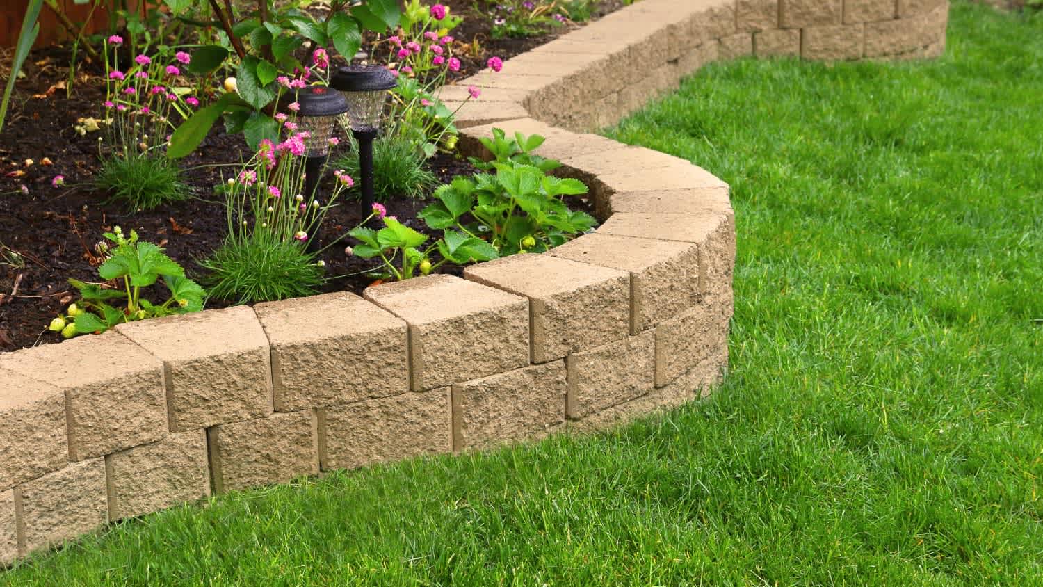 A stone wall in garden with artificial grass
