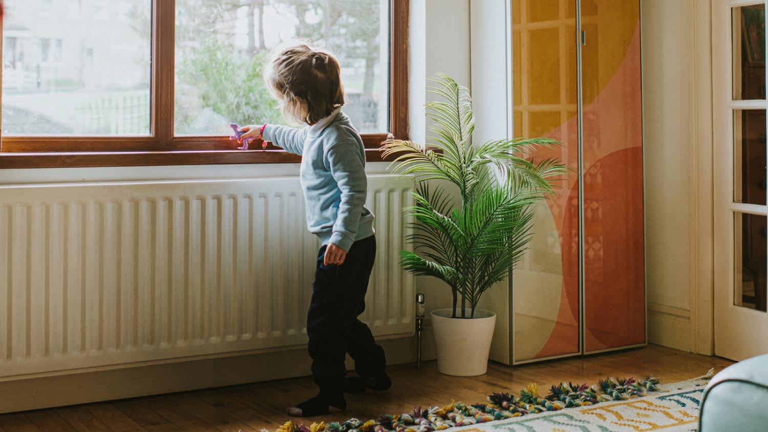 A girl playing next to a radiator