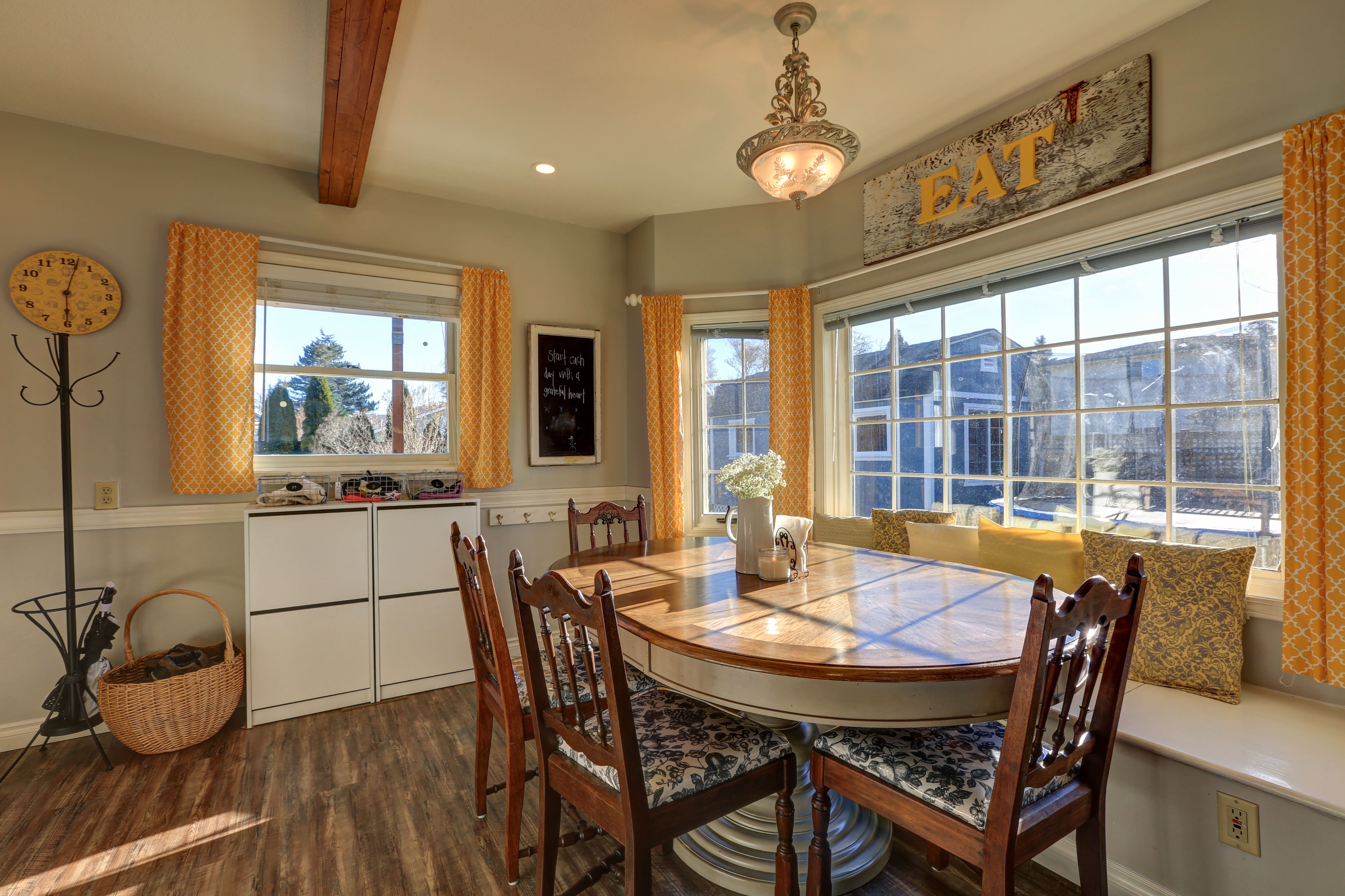 A breakfast nook with an oval table, bench seating, and yellow curtains