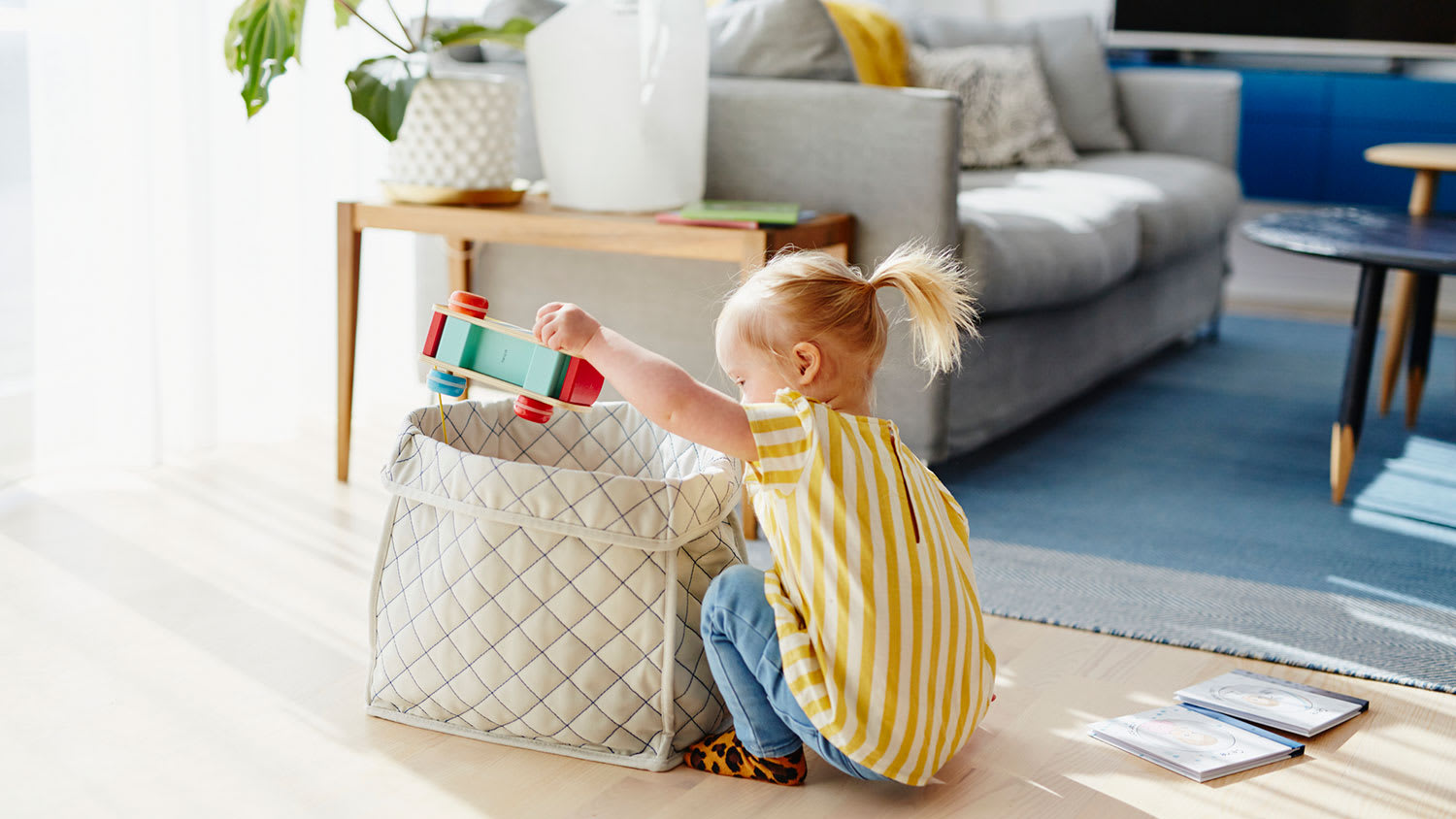 Girl sitting on the floor taking toys out of a box