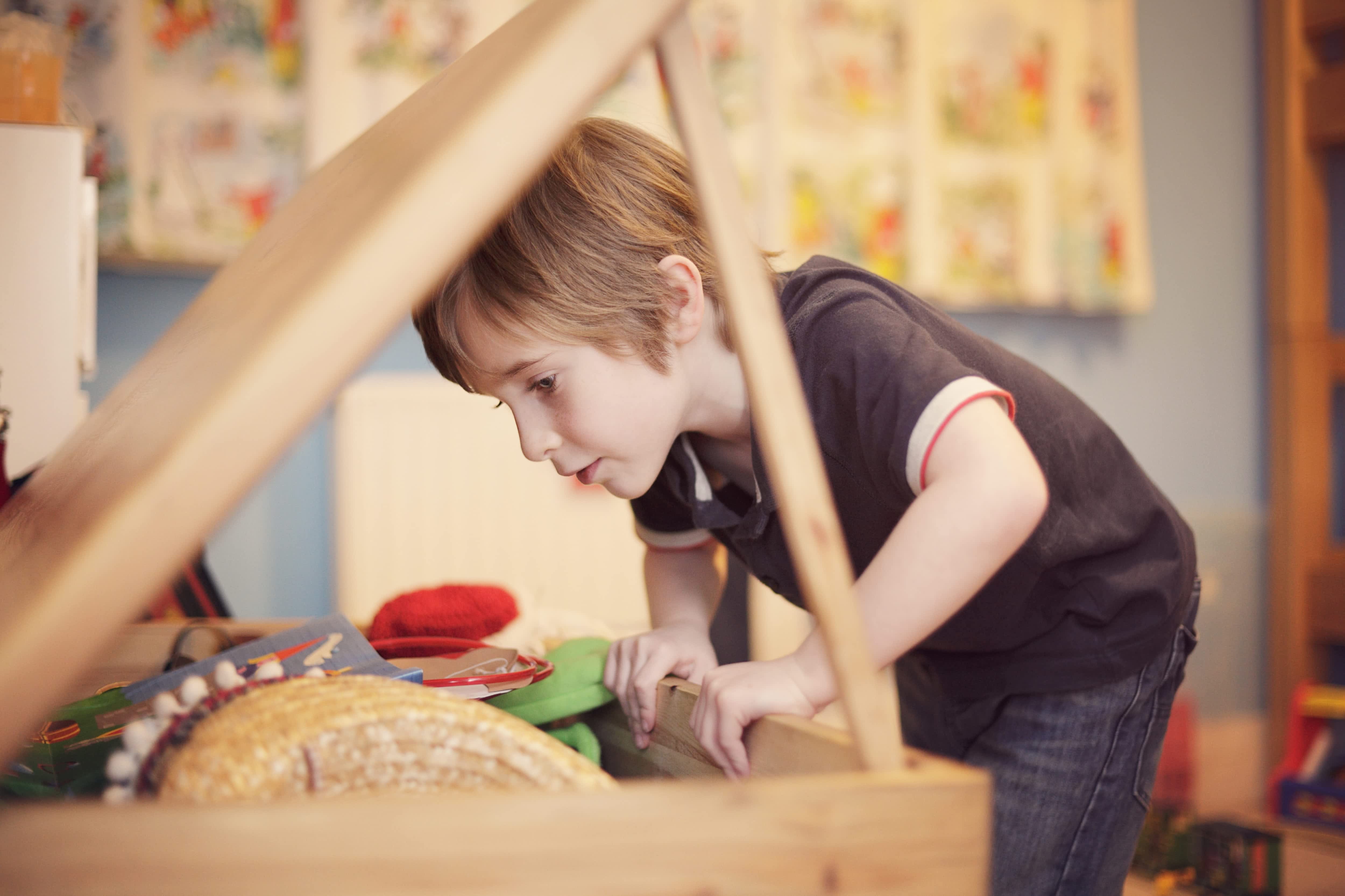 A young boy looking for toys in a toy chest
