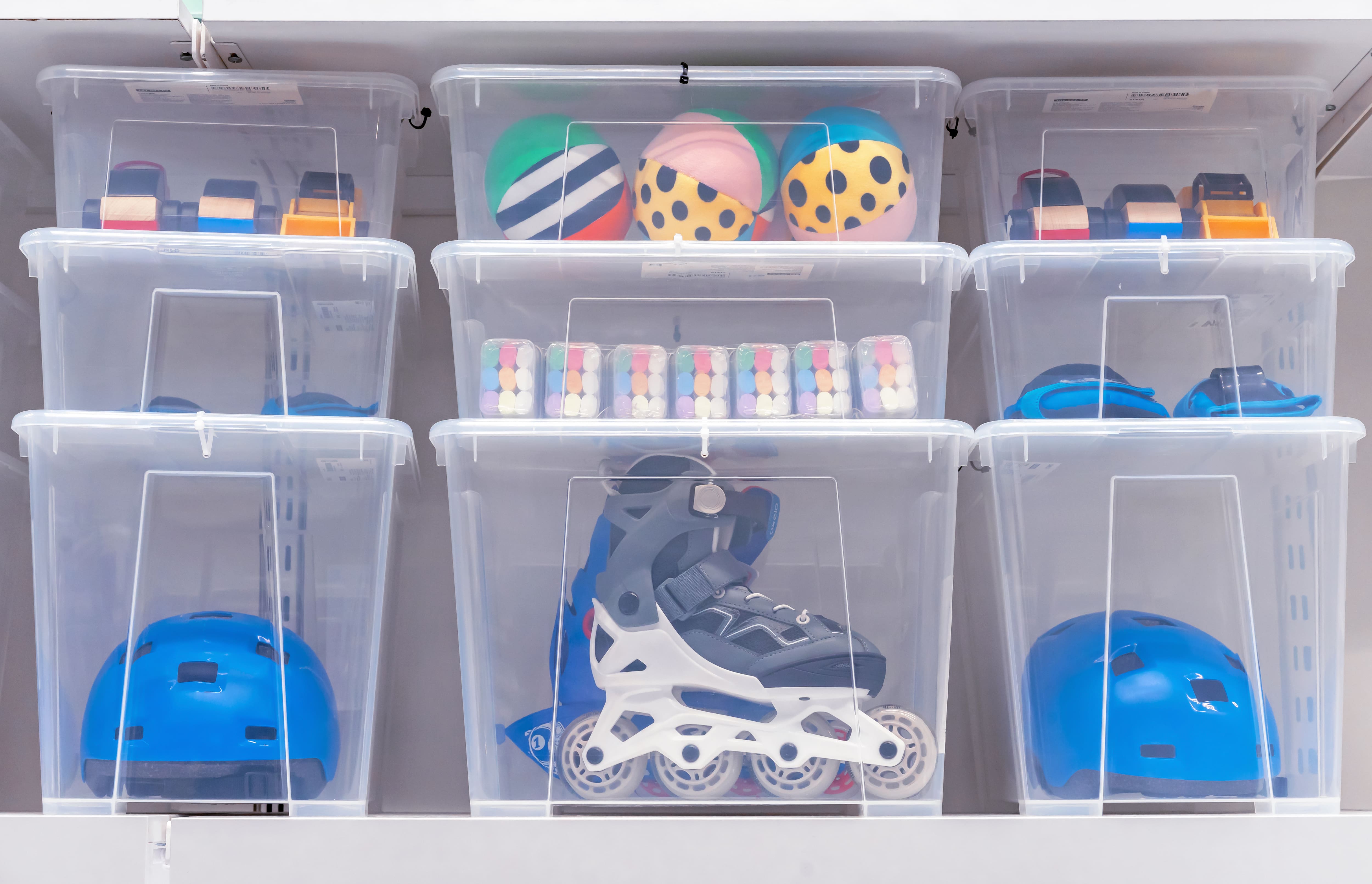 Rollerskates, helmets, and other toys stored in clear plastic bins of various sizes