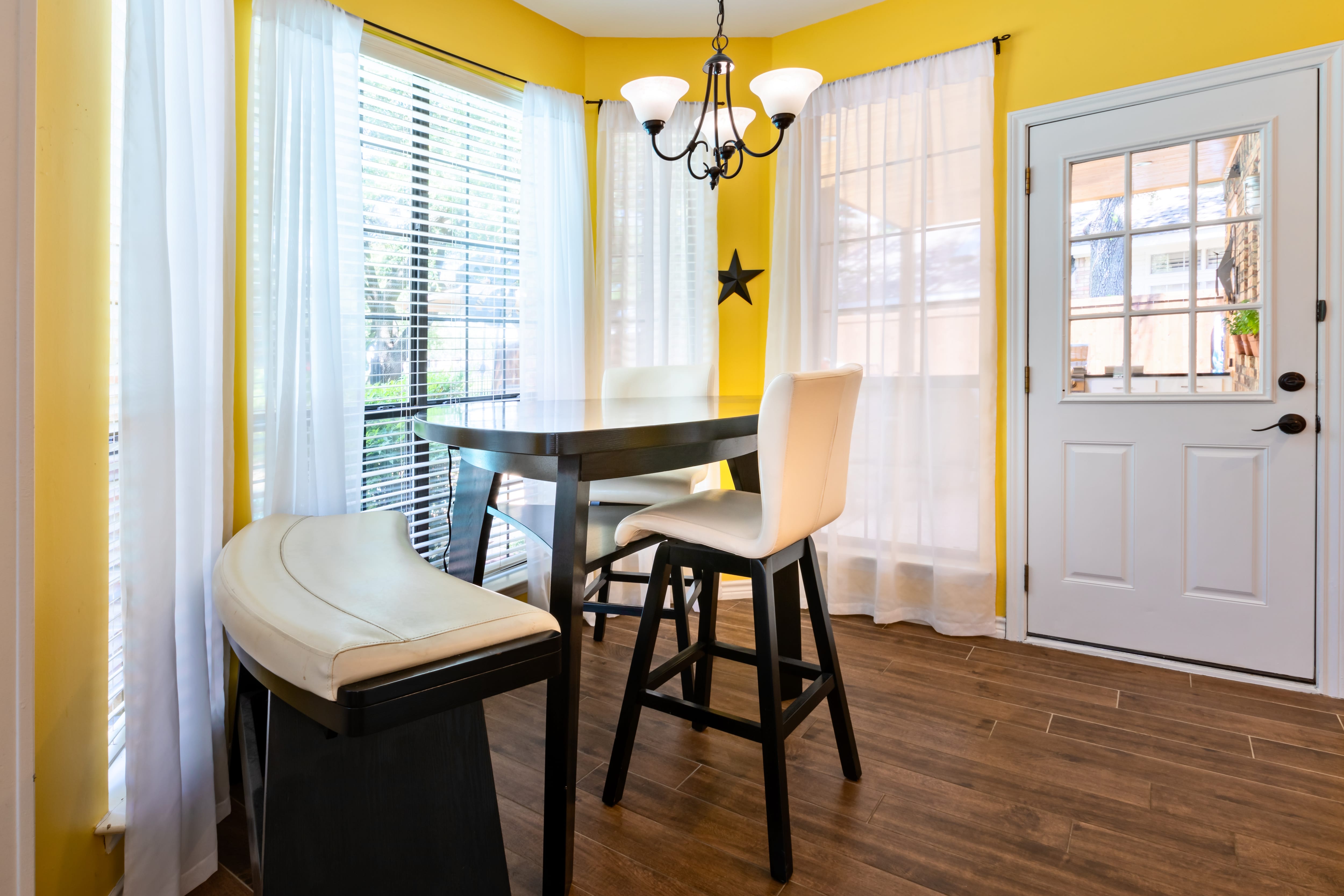 A yellow breakfast nook with a high-top table, chairs, and bench