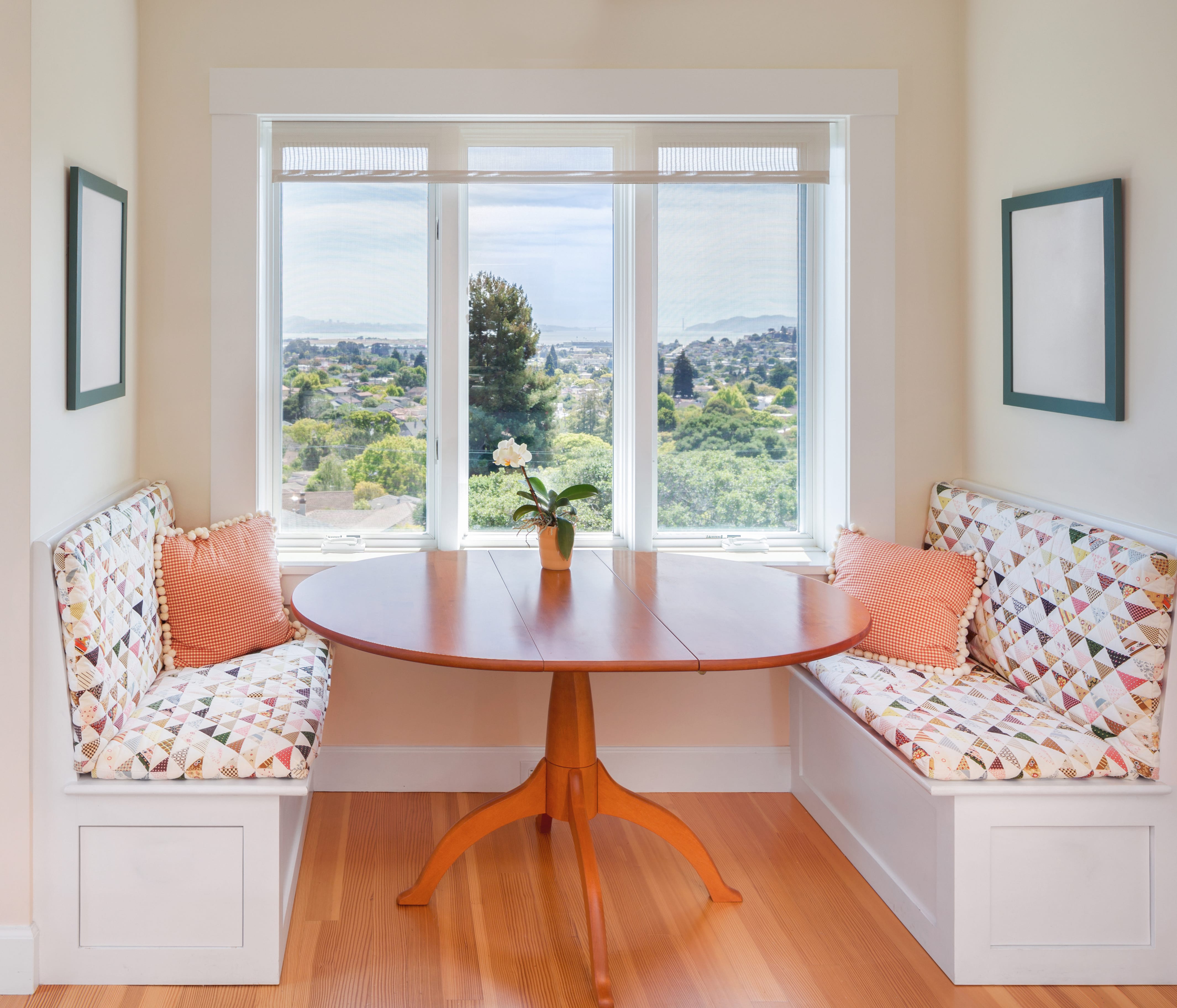 A bright breakfast nook with a wooden pedestal table next to a window with a view