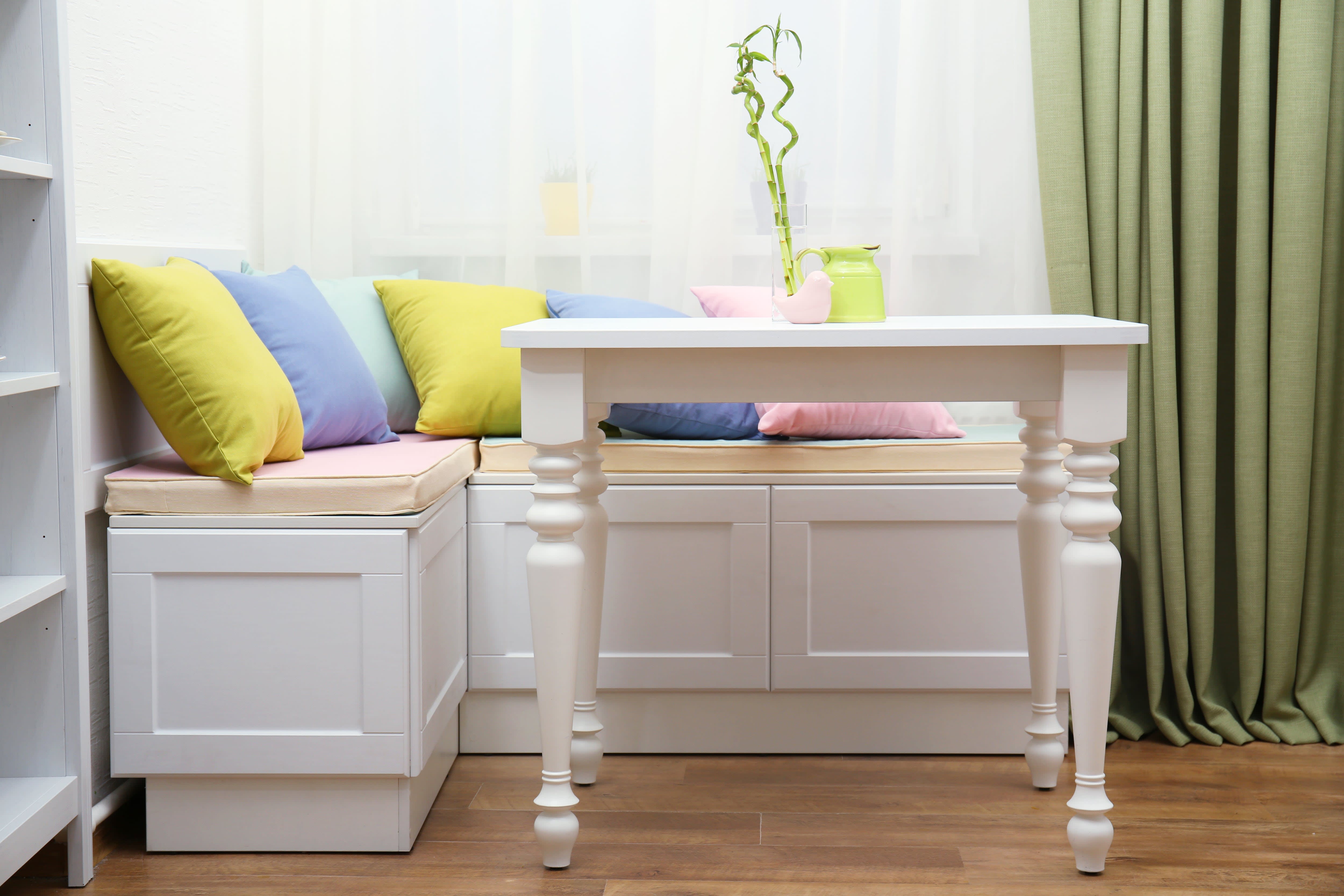A small kitchen nook with upholstered benches and pastel throw pillows