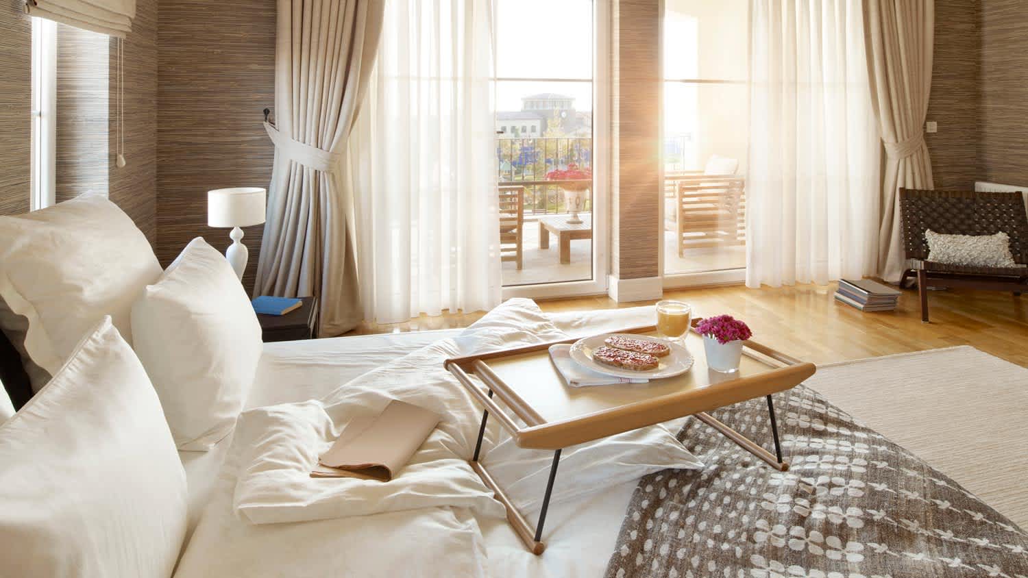 A sunlit bedroom with white draperies