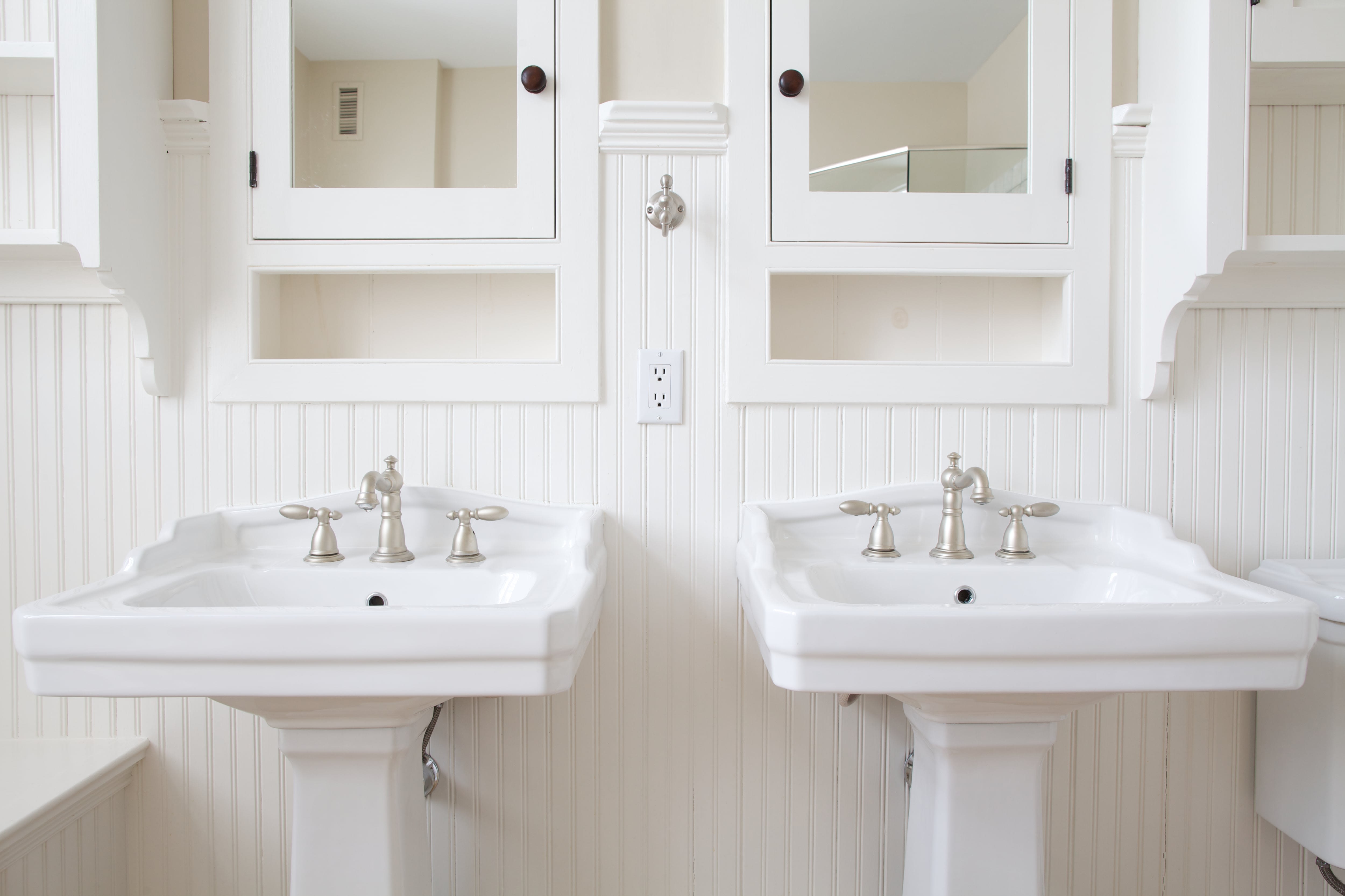 Built-in mirror cabinet in white-on-white bathroom
