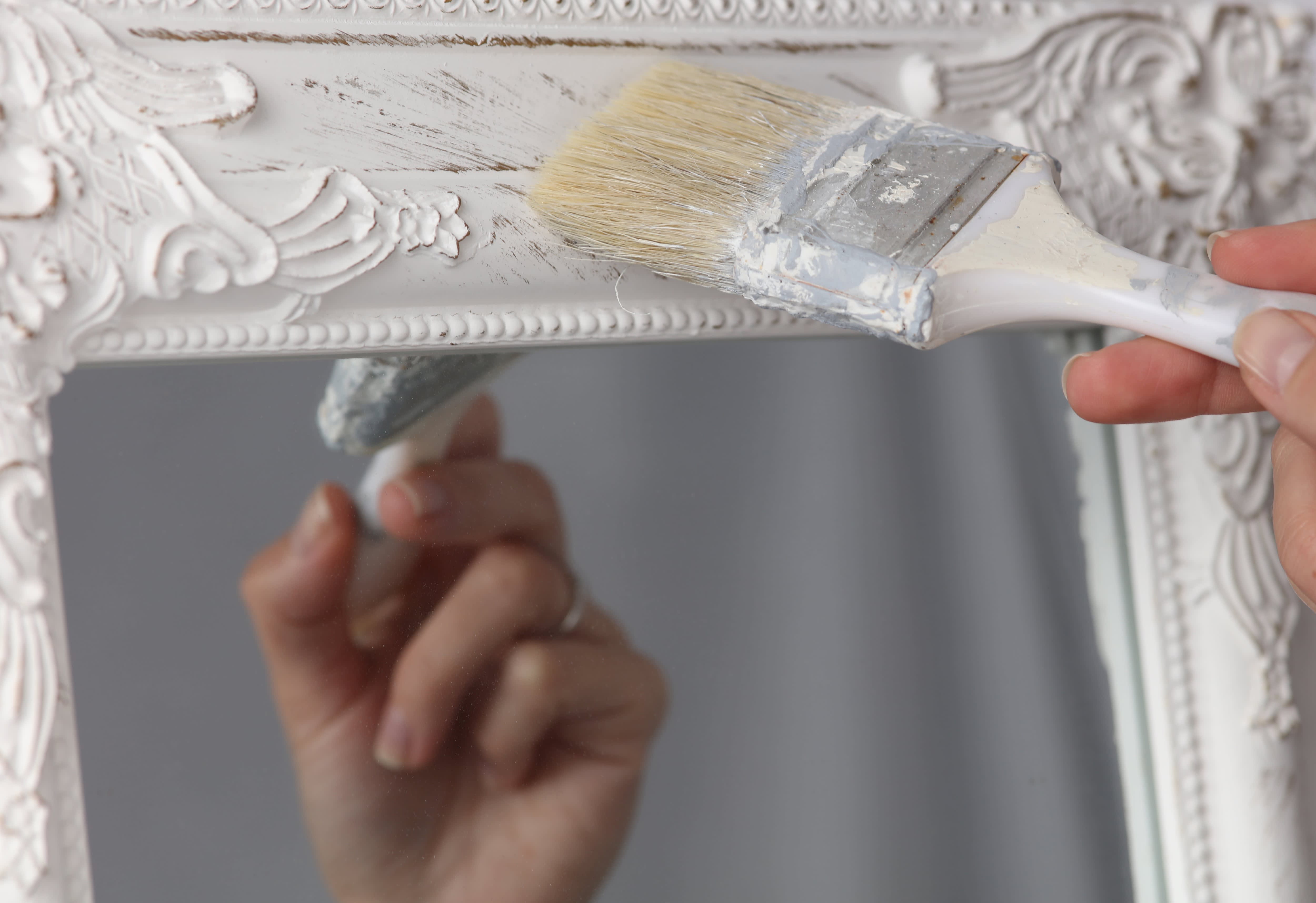 Woman painting over antique mirror with angled paintbrush