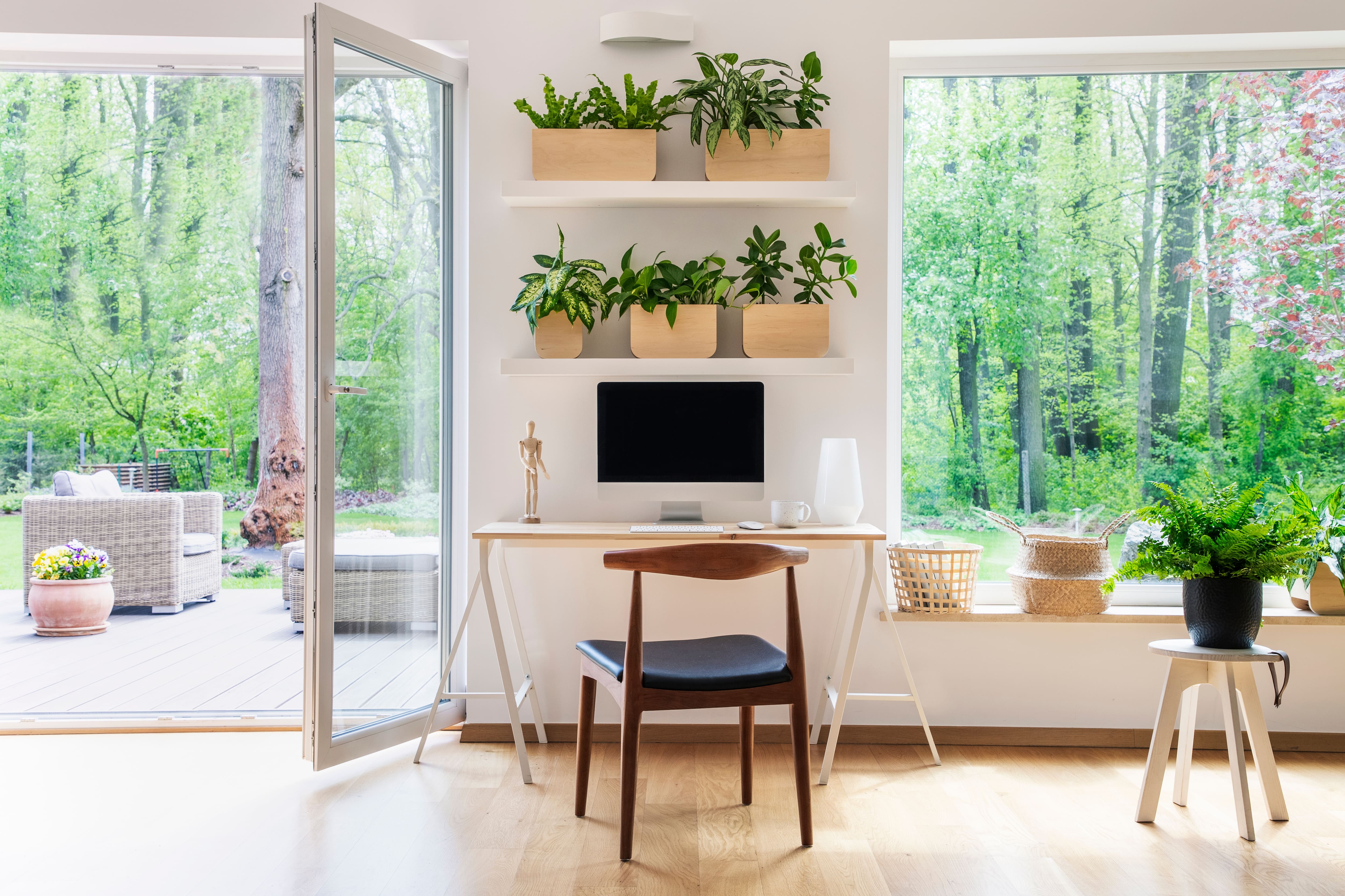 Bright home office with a desk, laptop, brown wooden chair, and big windows