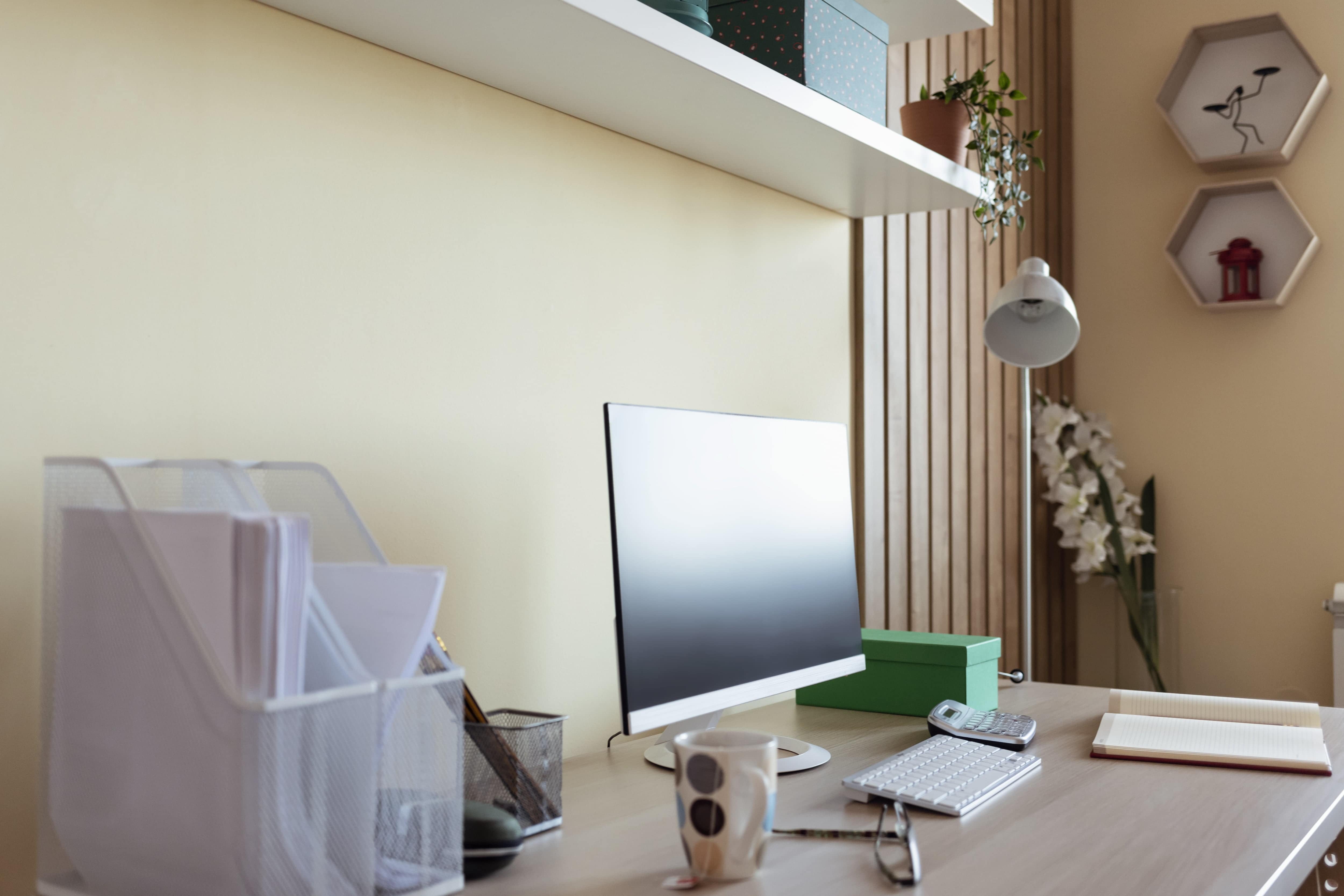 Home office space with a computer, keyboard, calculator, lamp, and notebook