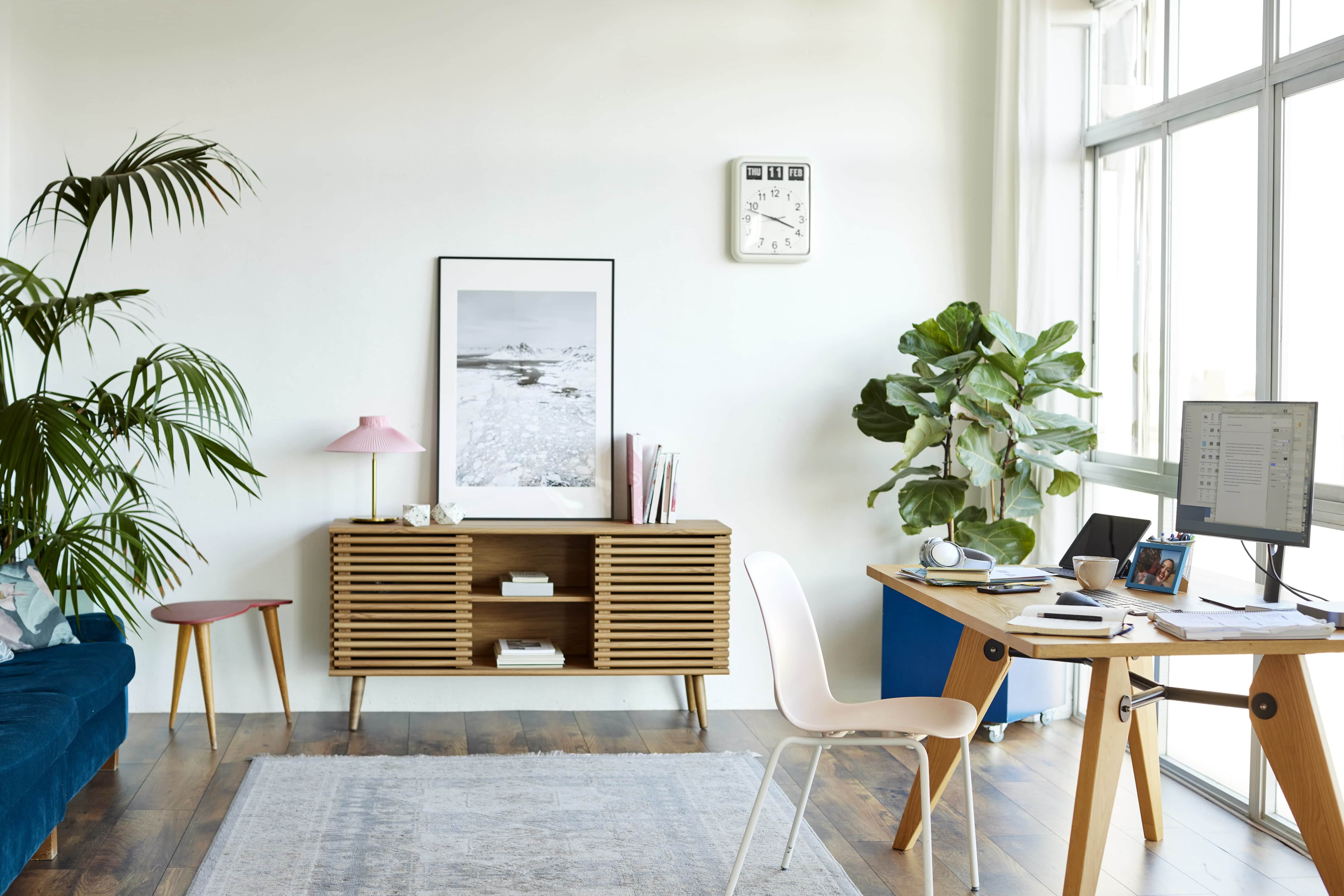 Bright home office with wood floors, a neutral rug, and mid-mod style furniture