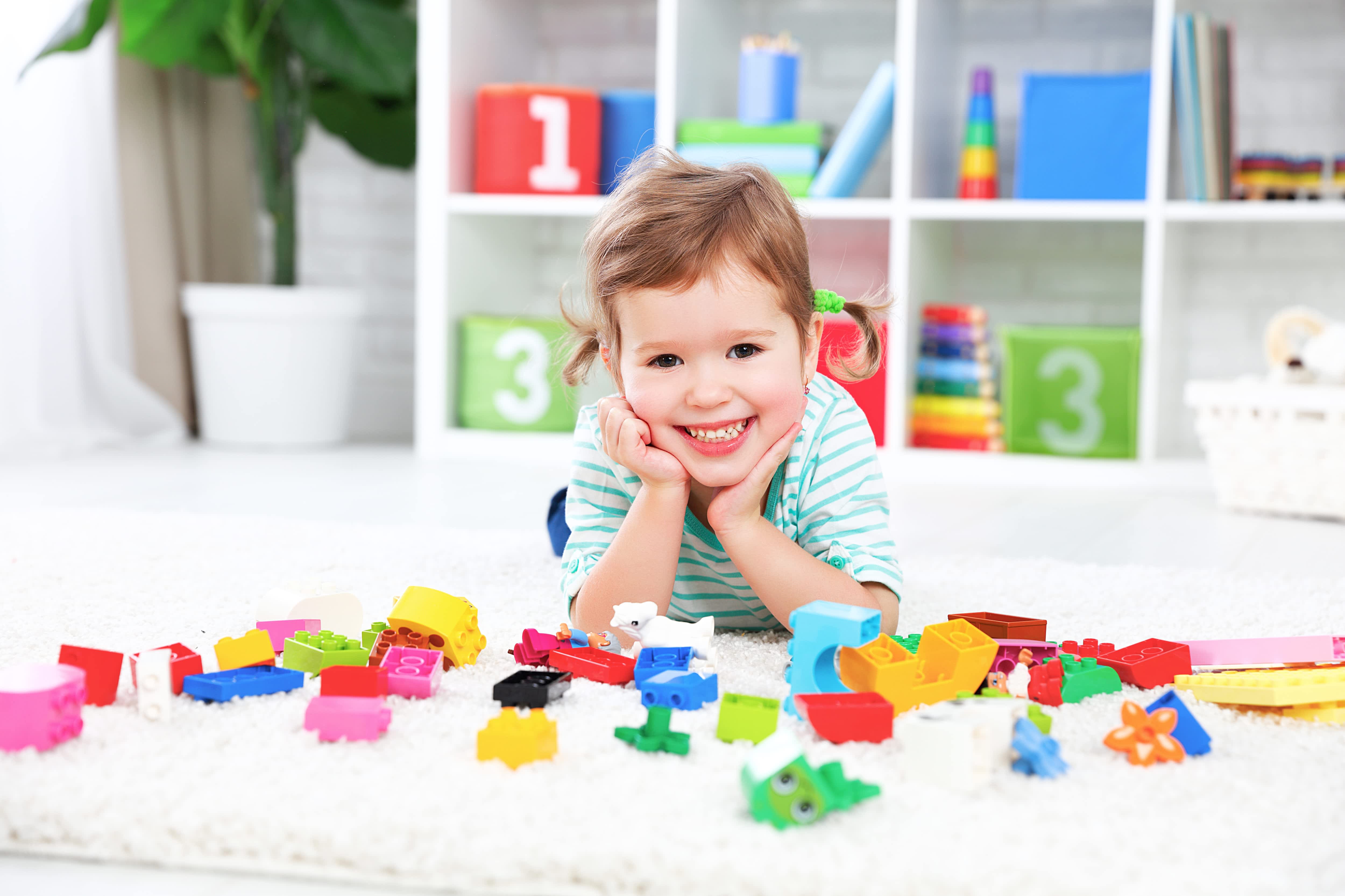 A happy young child playing with toys in an organized play room