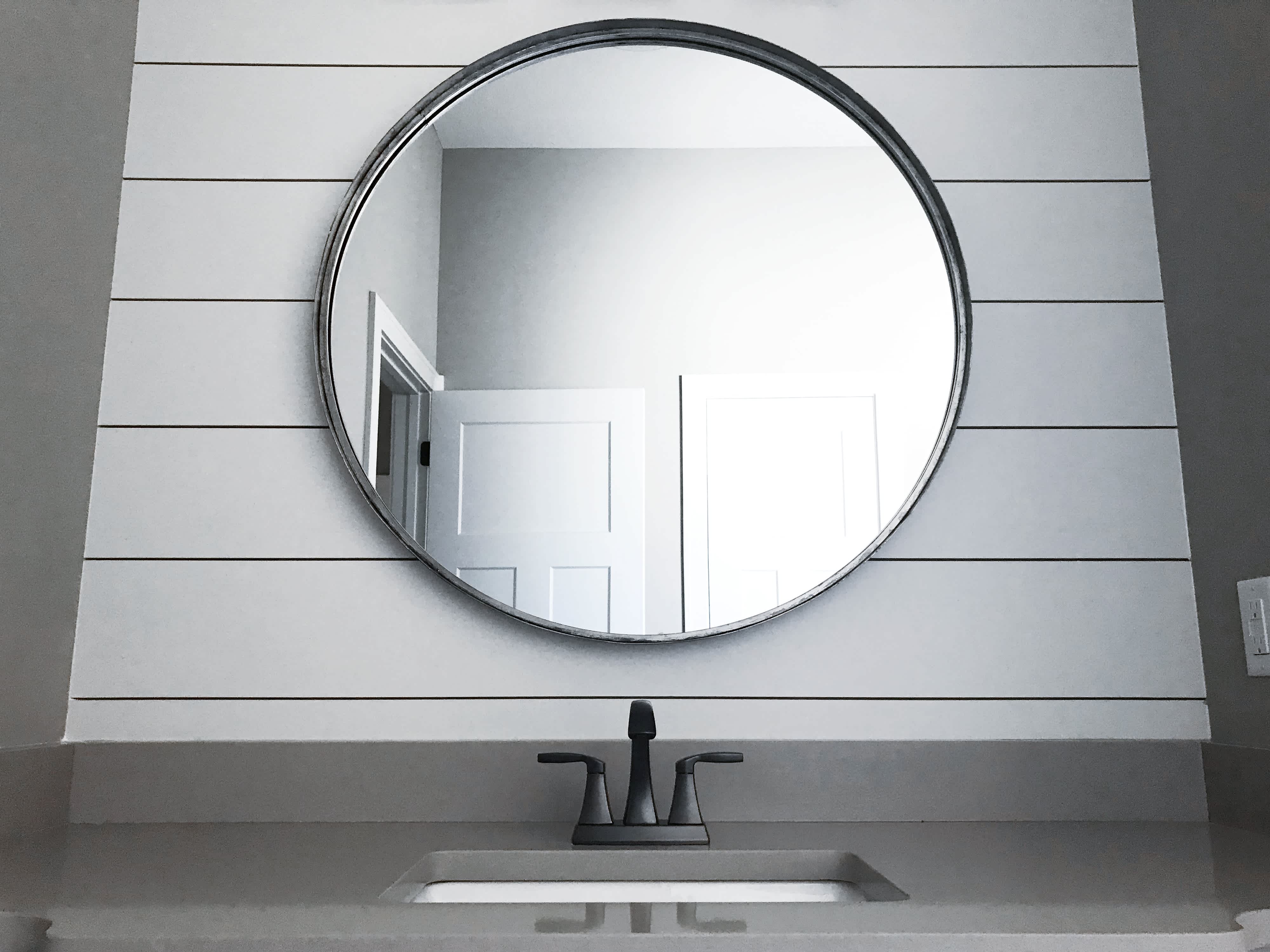 Bathroom interior with circular mirror against shiplap accent wall