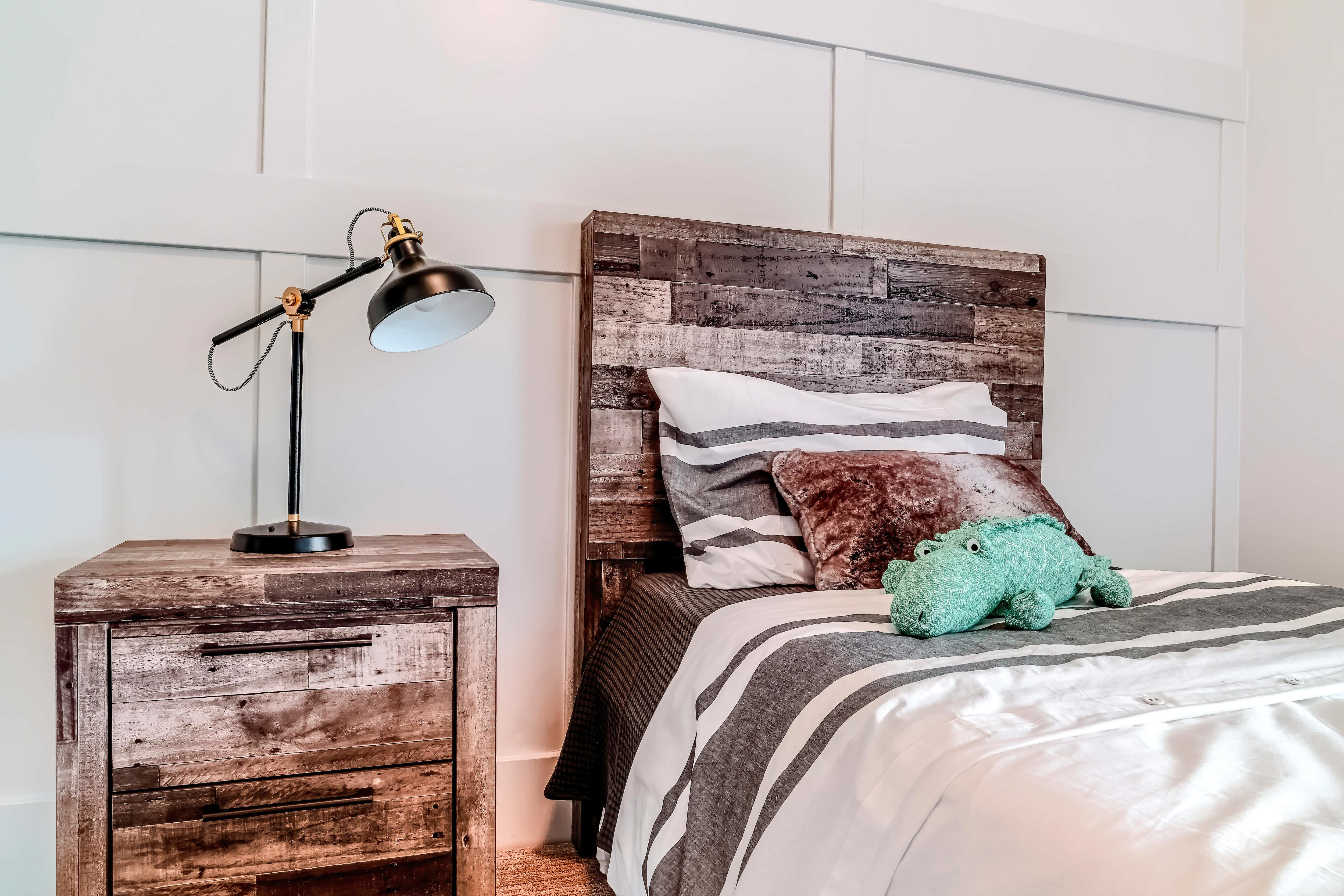 A clean bedroom with a headboard and matching dresser made from reclaimed wood