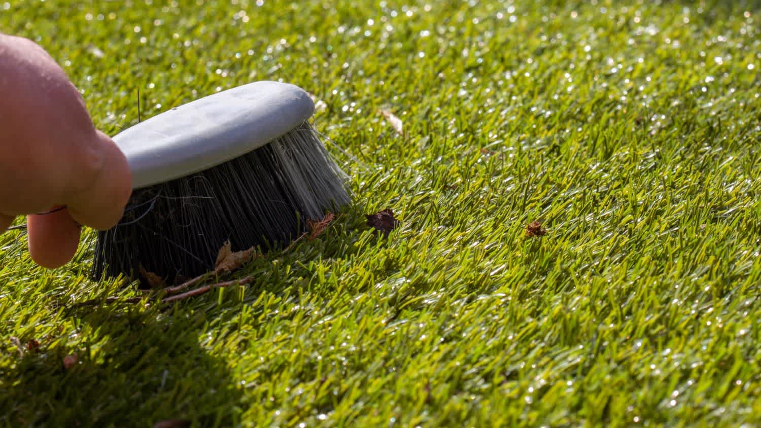 A man brushing rubbish on artificial grass
