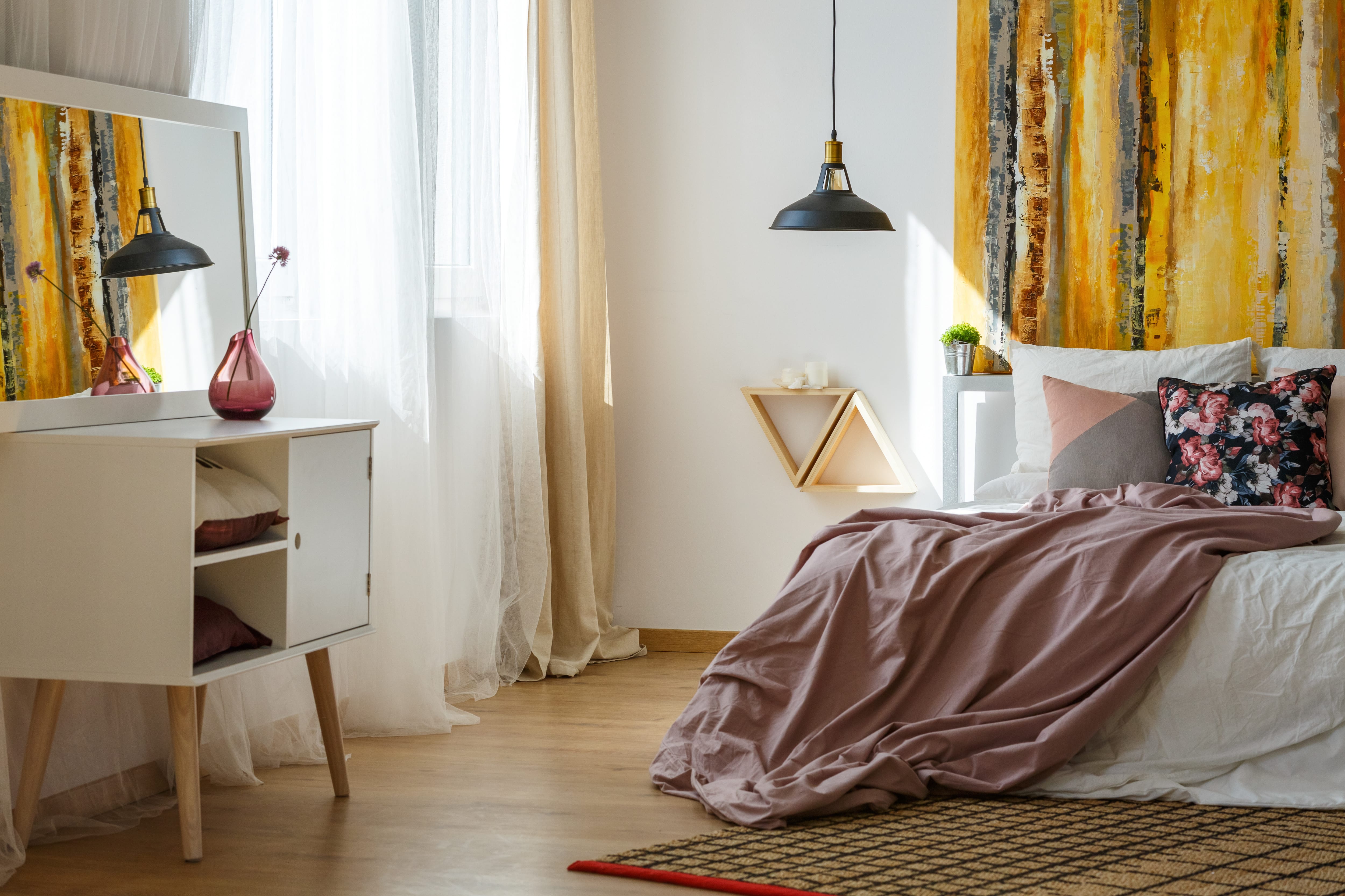 A modern bedroom with a large yellow canvas above the bed