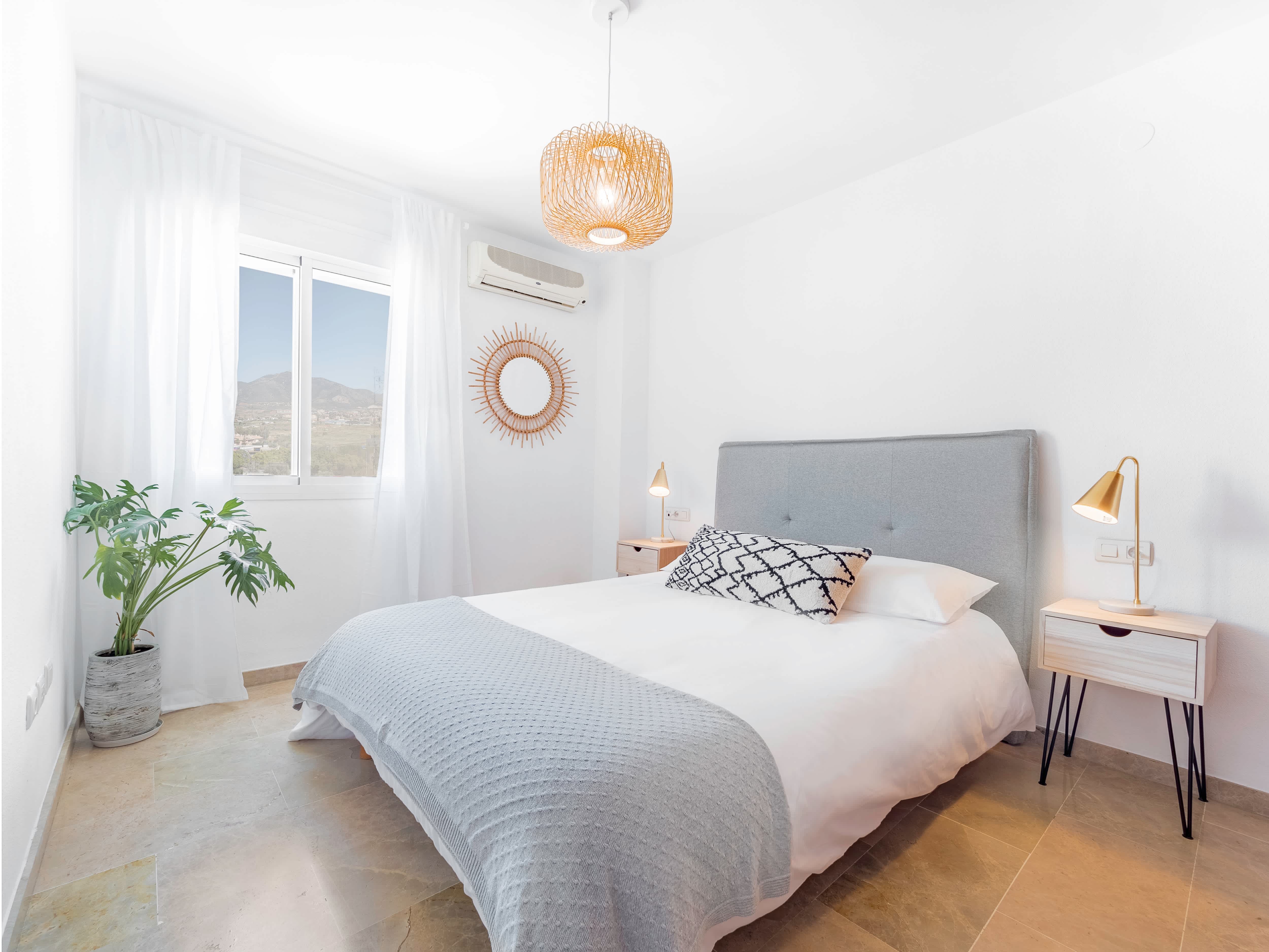 A bed with a gray felt headboard in a bright minimalist bedroom