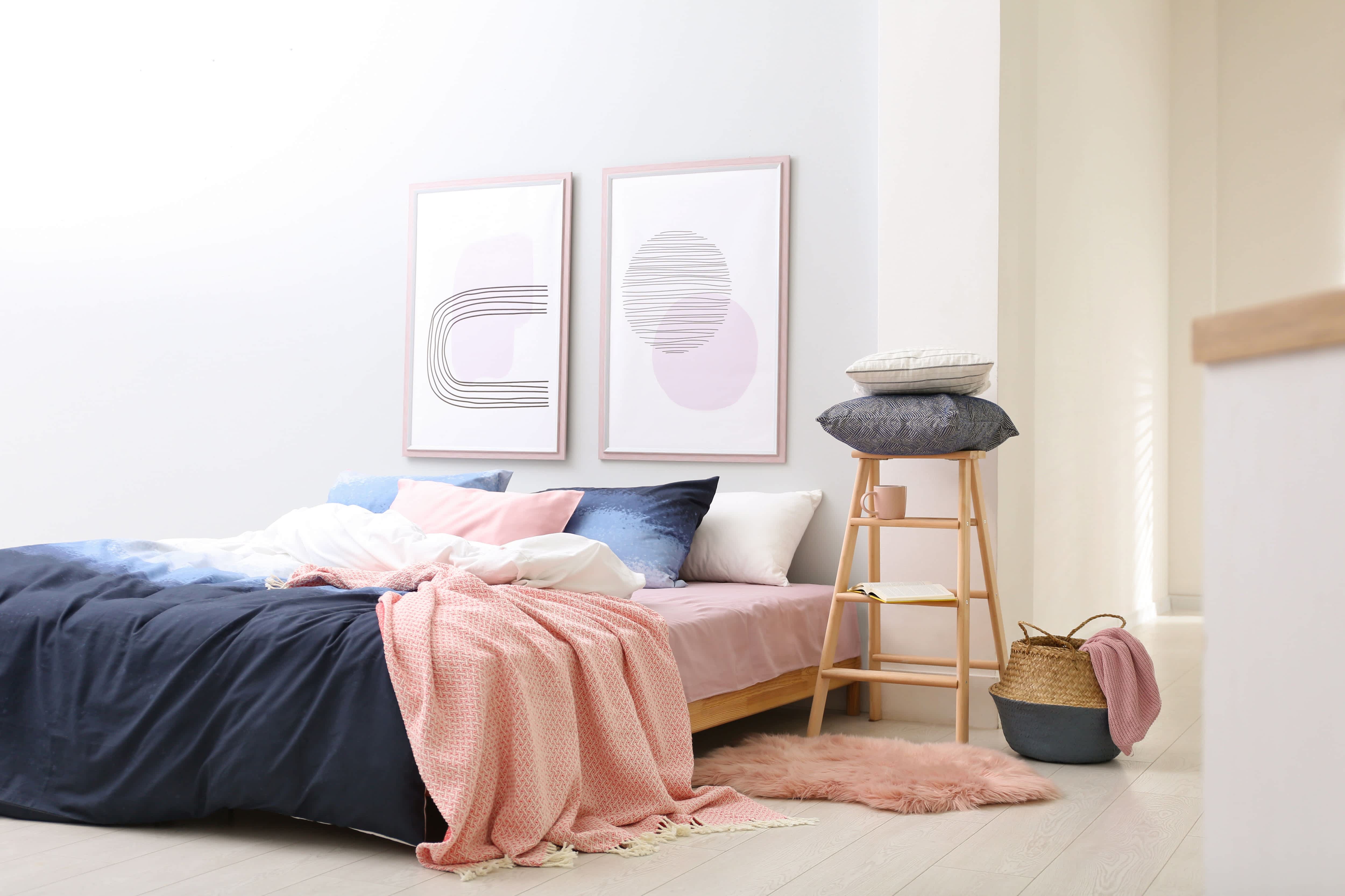 A large modern bedroom with two large framed artwork prints mounted above the bed