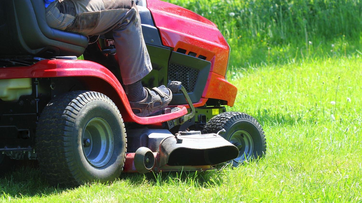 A gardener driving a riding lawn mower