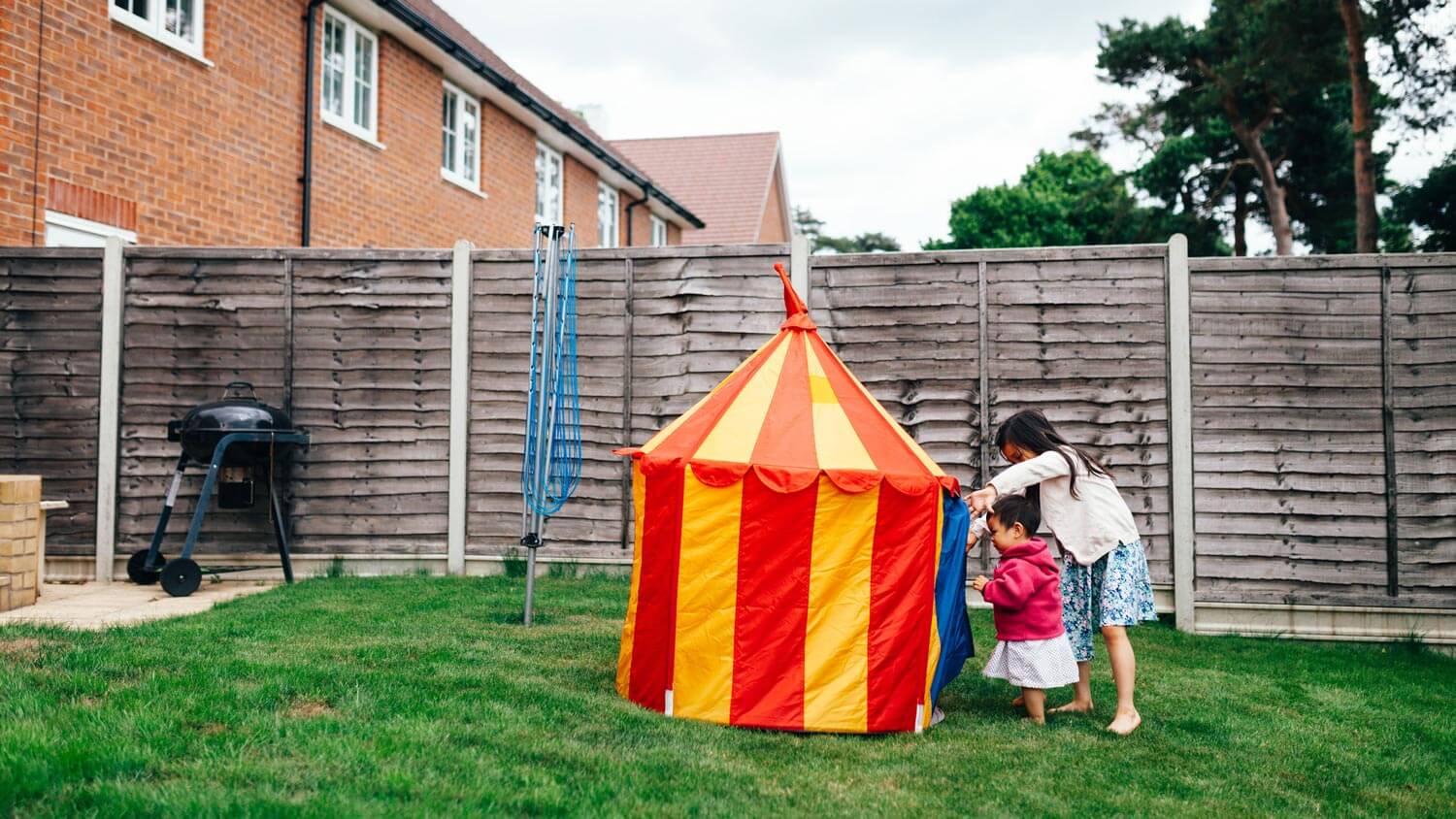 Two girls getting in a tent in their yard