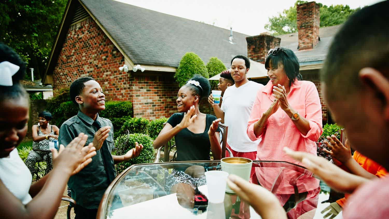 A family gathering around a glass table in the backyard