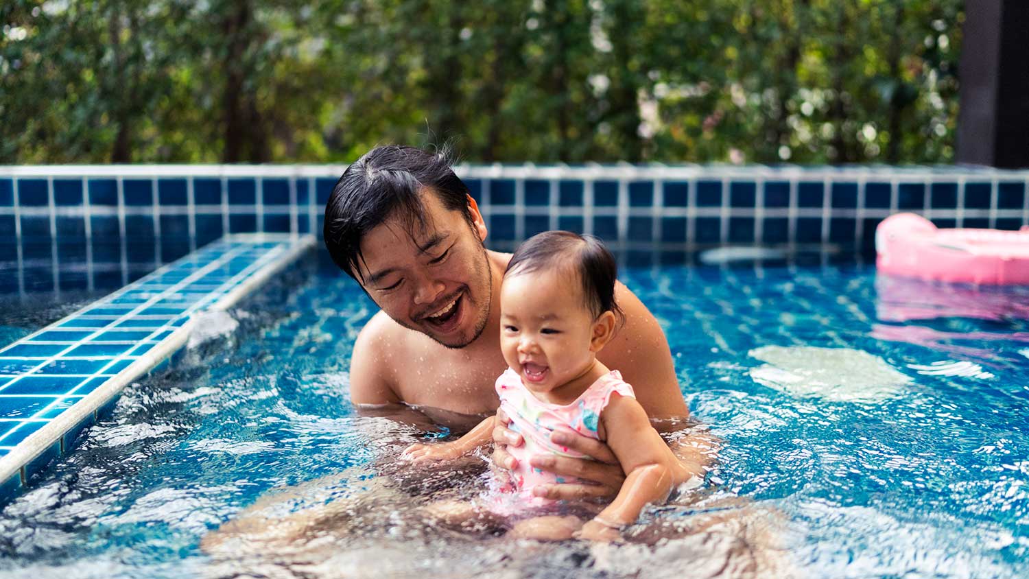 Father and toddler daughter playing in the swimming pool