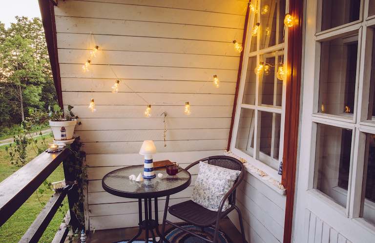 small patio with round coffee table and chair, with string lights hanging from ceiling
