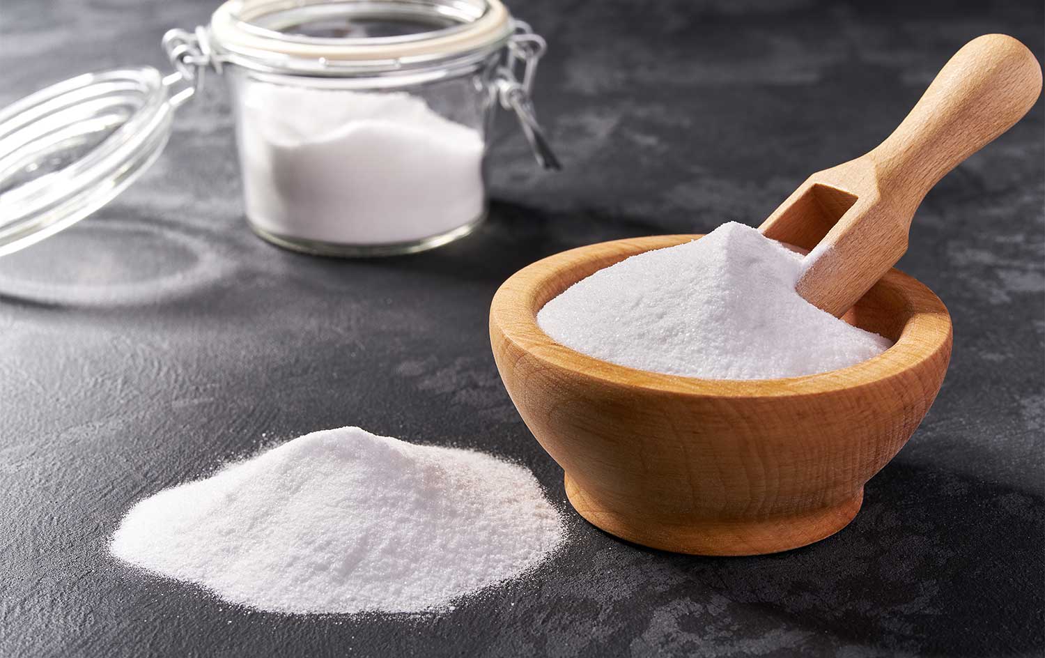 Wooden bowl with baking soda on a black background