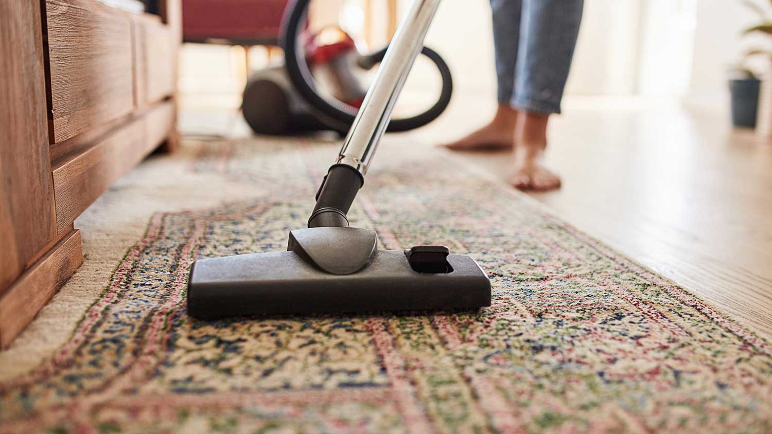 Closeup of a woman vacuuming rug in the living room