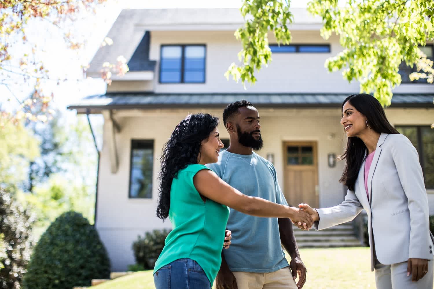 A couple meeting with real estate agent in front of home