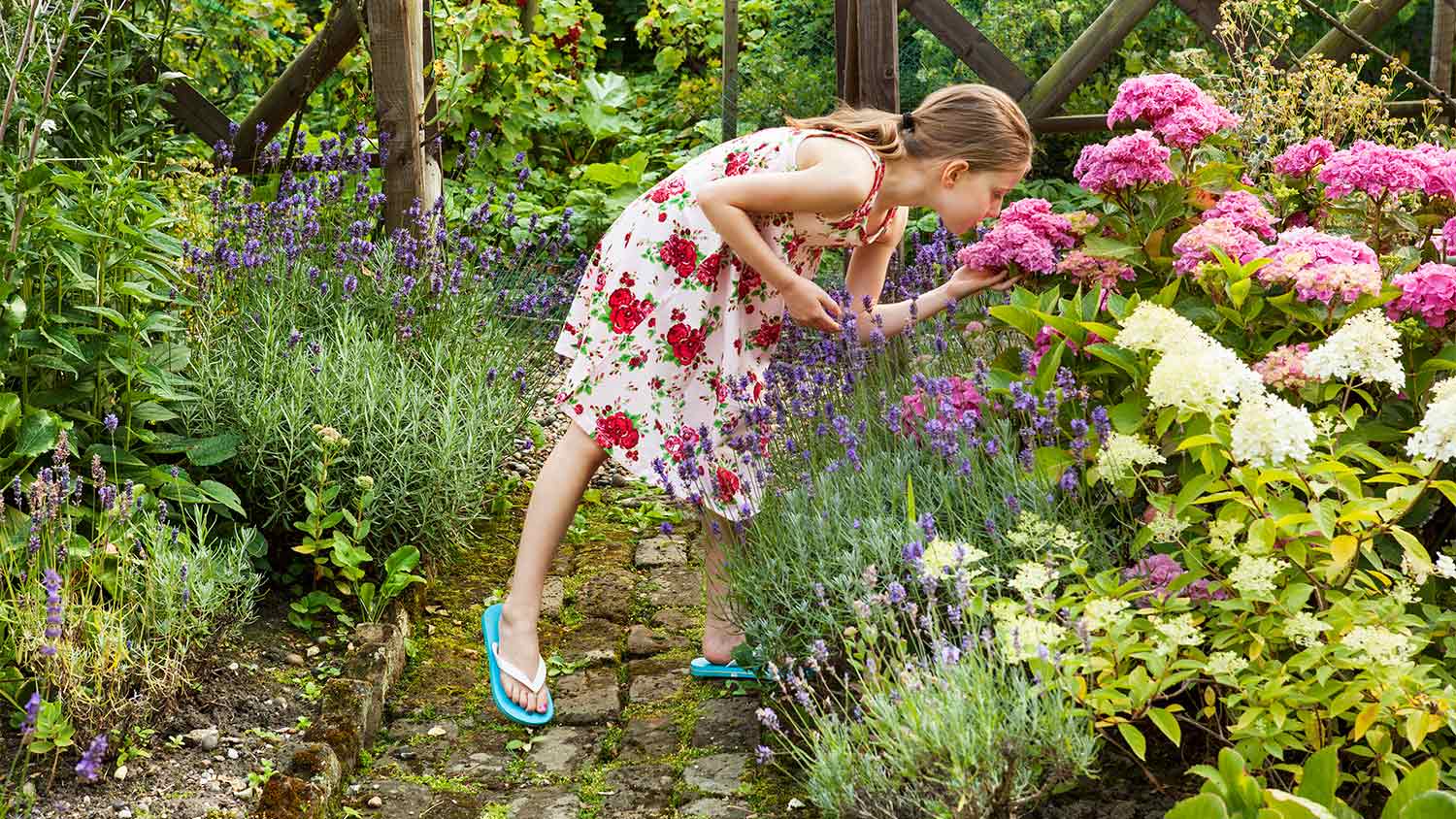 Little girl smelling flowers in the garden